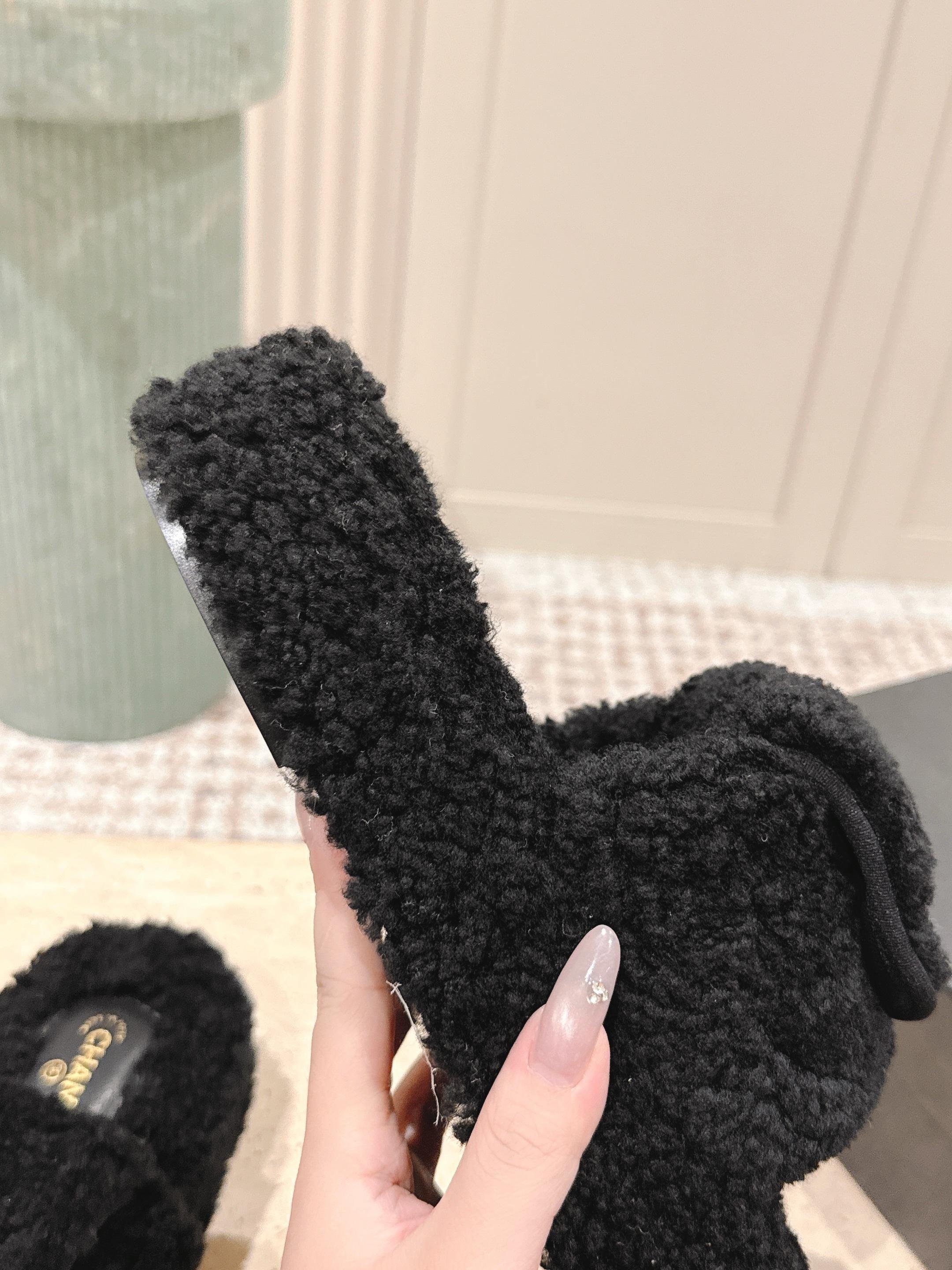Luxury black Chanel shearling slides with gold CC logo displayed on a textured pedestal - Hình 8