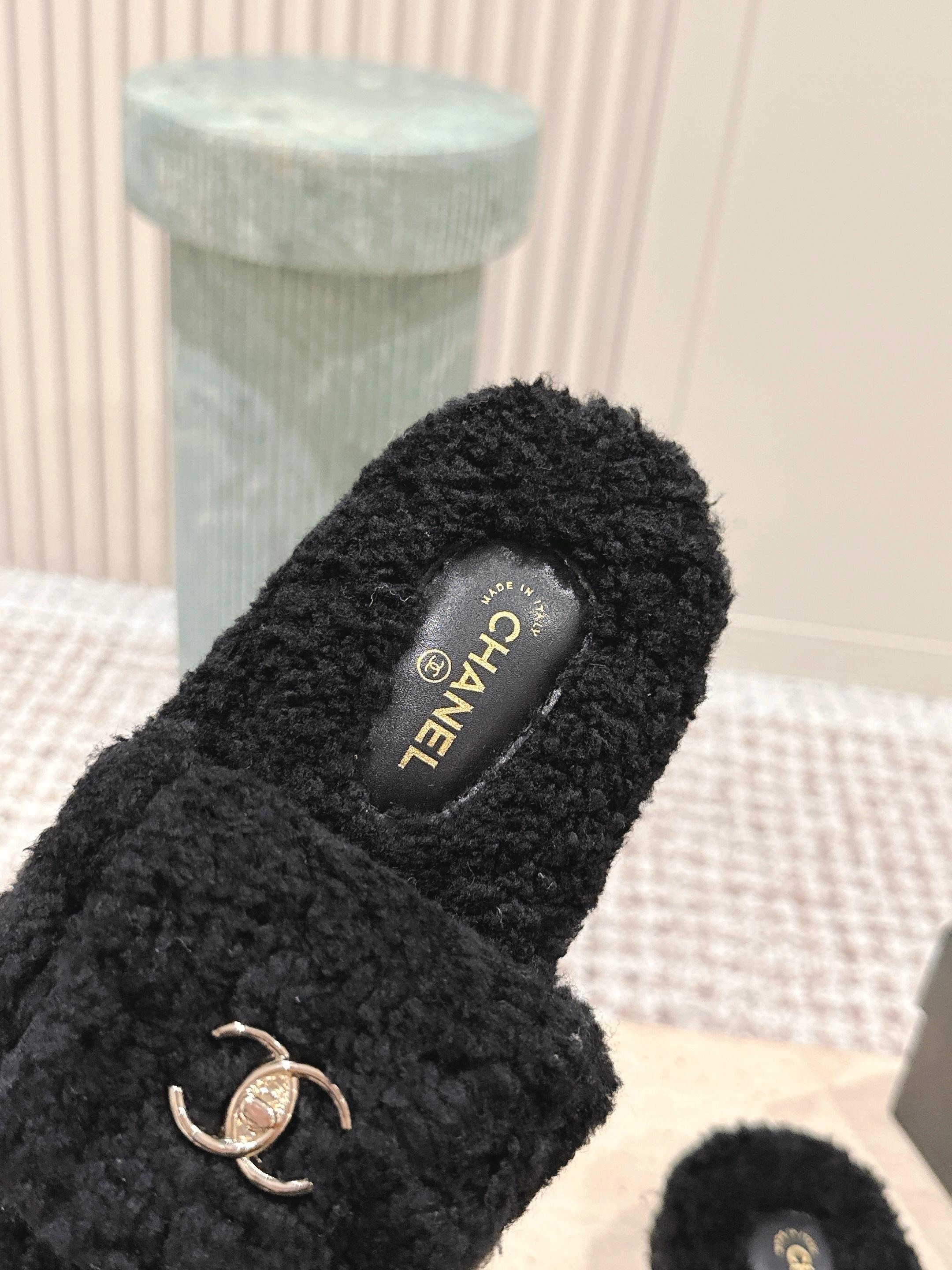 Luxury black Chanel shearling slides with gold CC logo displayed on a textured pedestal - Hình 7
