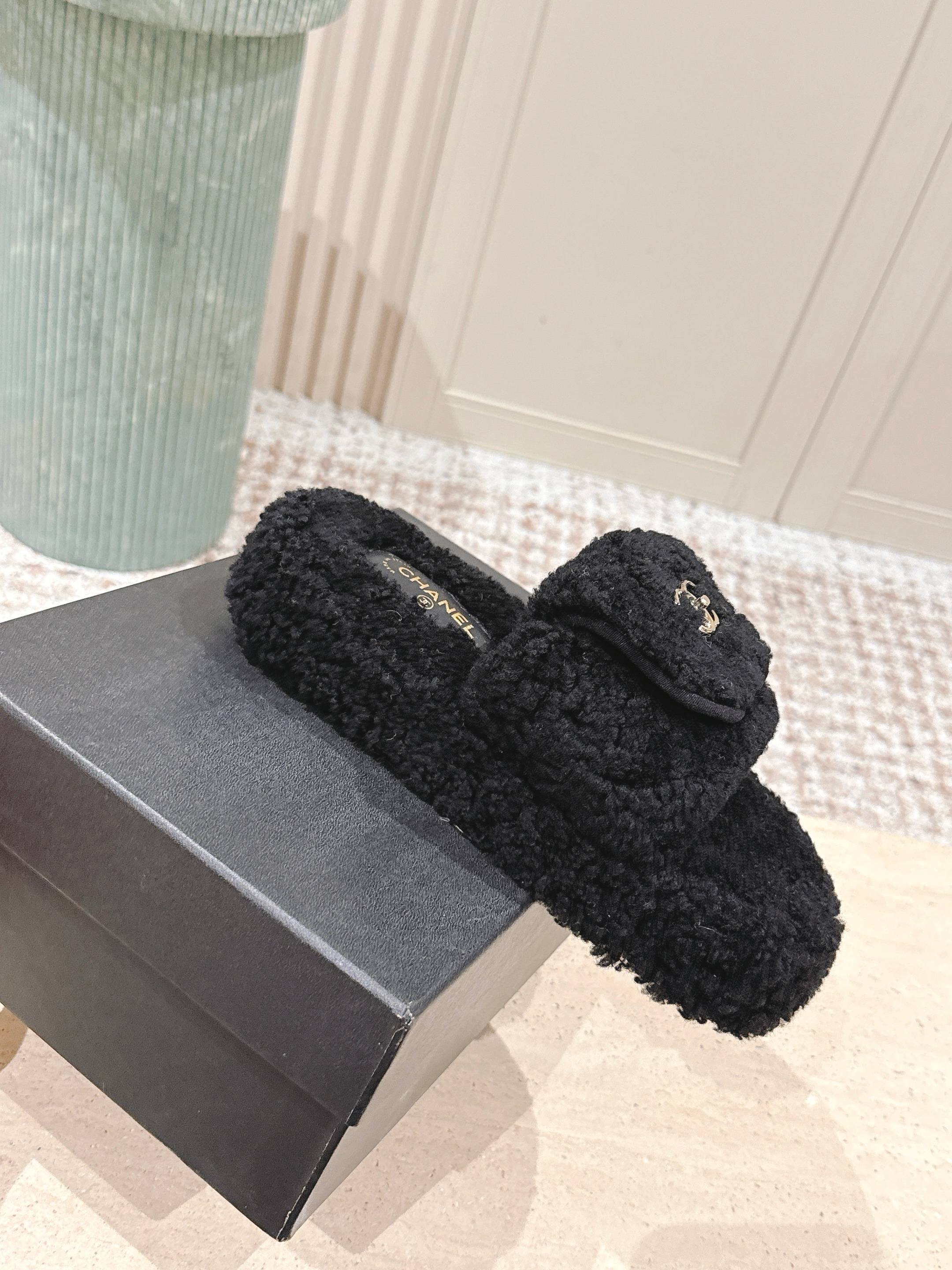 Luxury black Chanel shearling slides with gold CC logo displayed on a textured pedestal - Hình 3