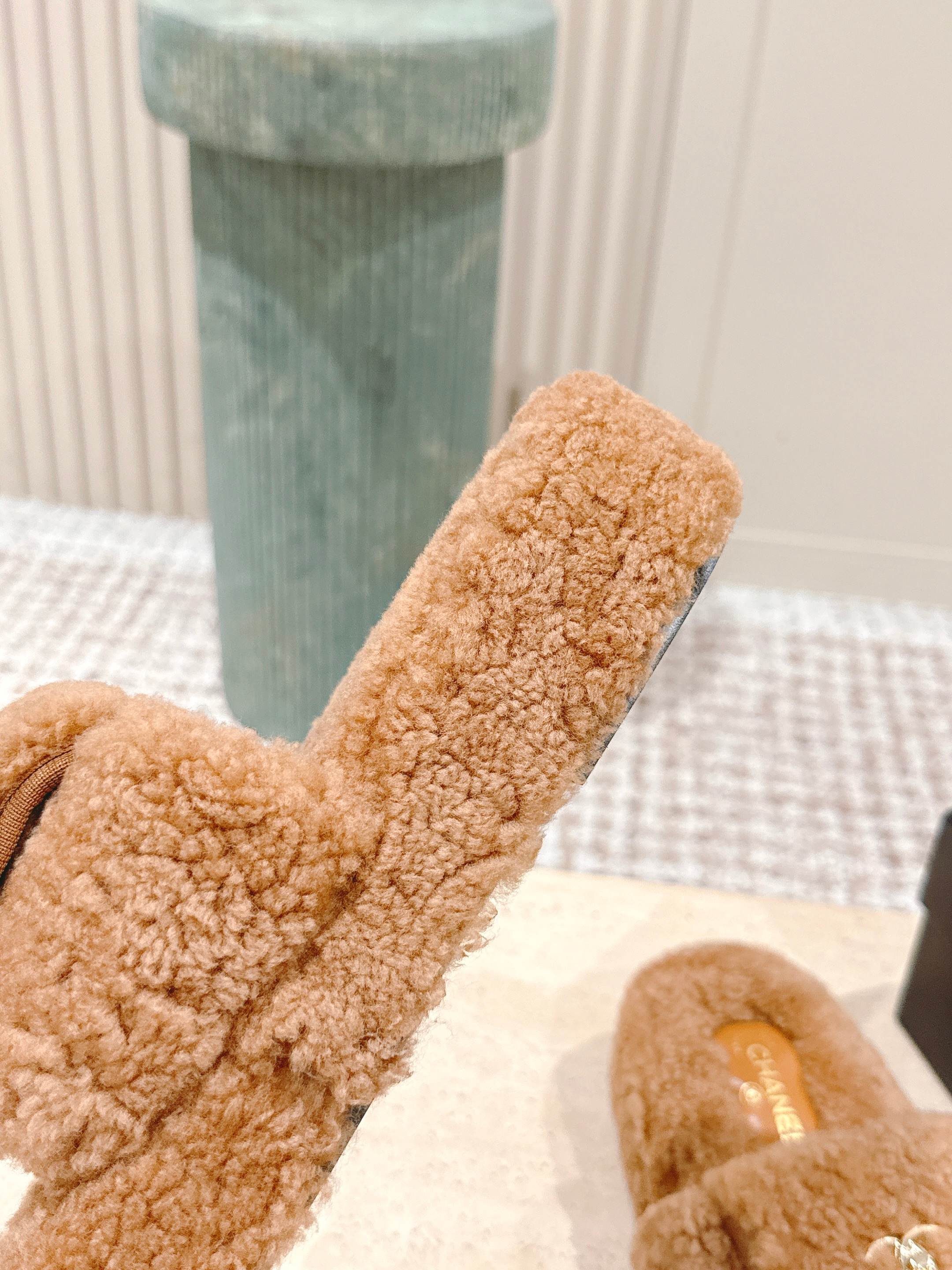 A pair of luxury Chanel shearling fluffy slide sandals in camel brown featuring gold CC logos on the straps. - Hình 8