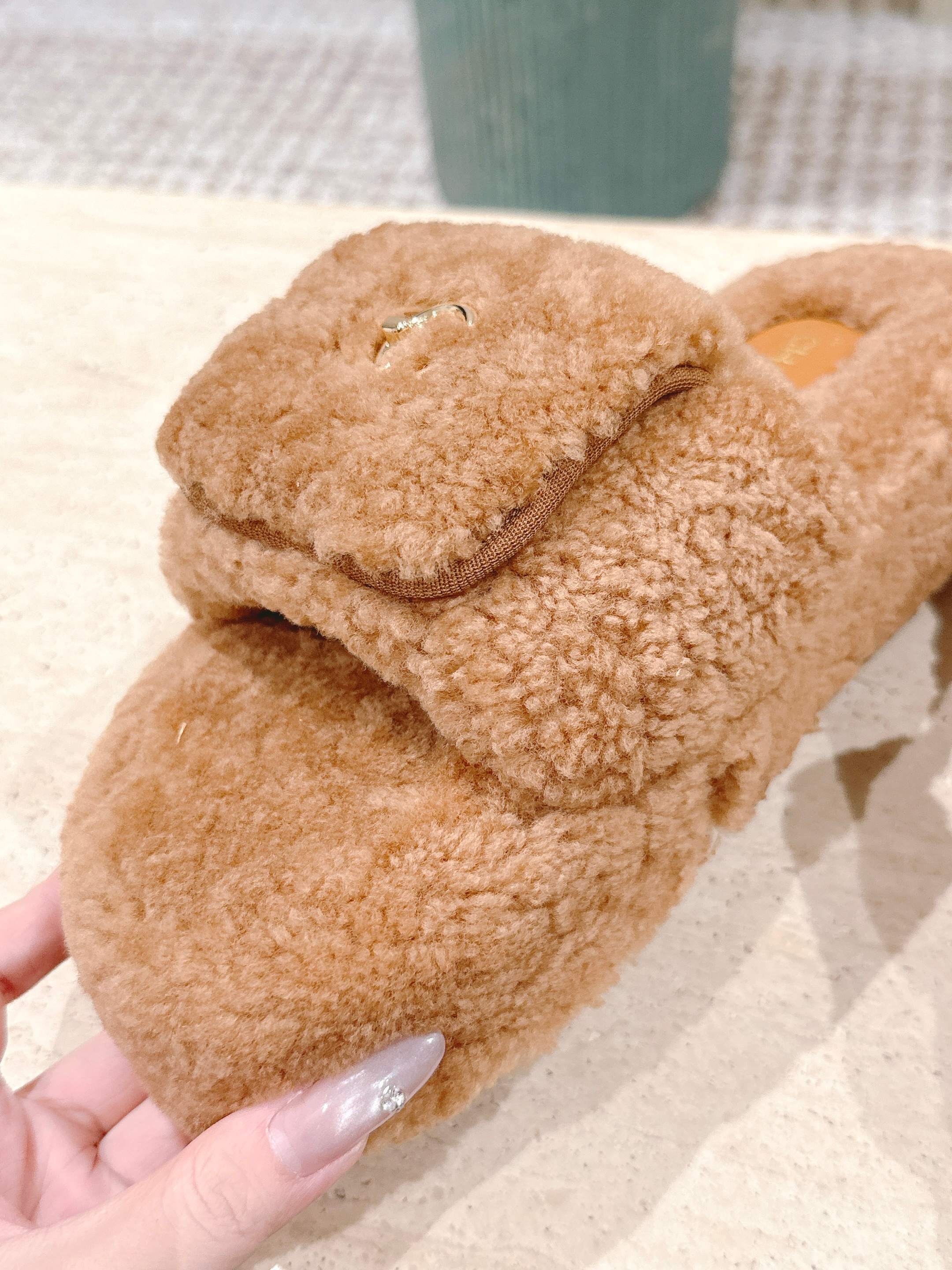 A pair of luxury Chanel shearling fluffy slide sandals in camel brown featuring gold CC logos on the straps. - Hình 6