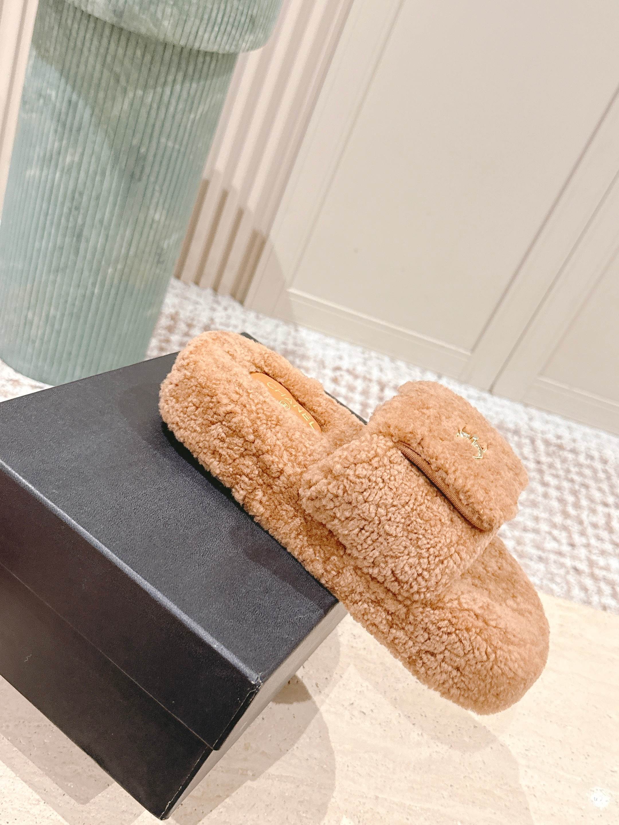 A pair of luxury Chanel shearling fluffy slide sandals in camel brown featuring gold CC logos on the straps. - Hình 4