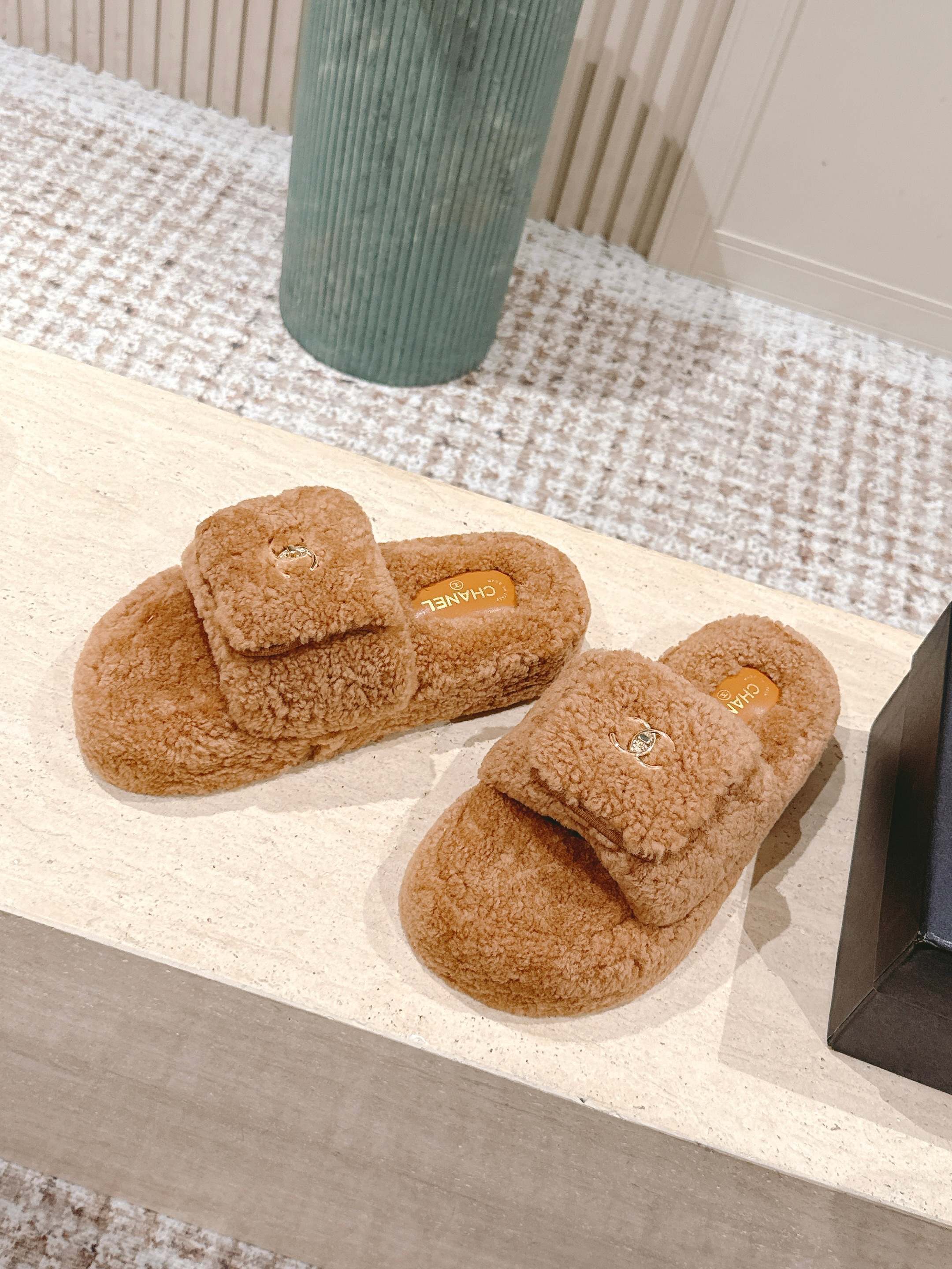A pair of luxury Chanel shearling fluffy slide sandals in camel brown featuring gold CC logos on the straps. - Hình 3