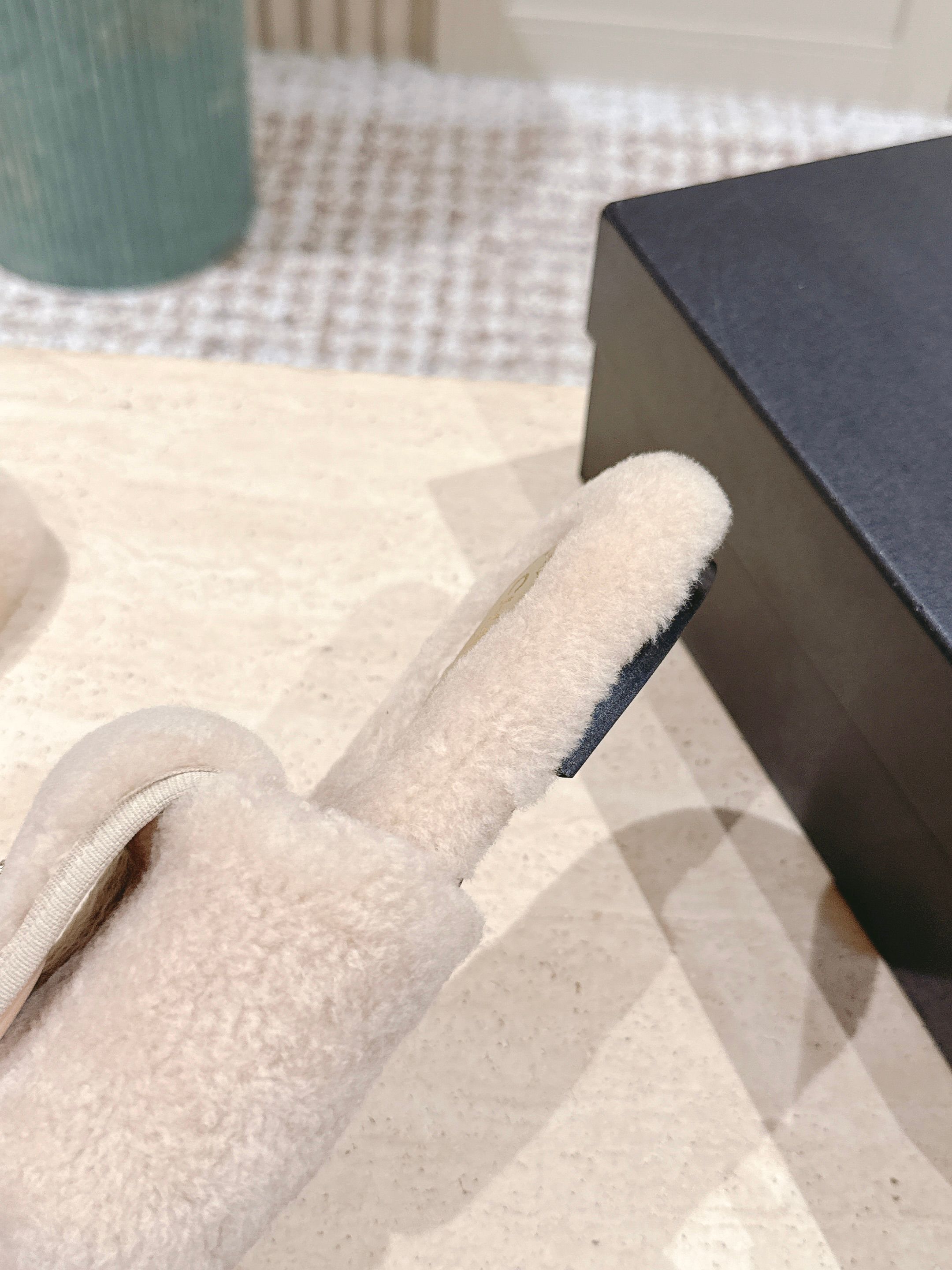 Luxury beige Chanel shearling slides with gold CC logo hardware on a display stand - Hình 8
