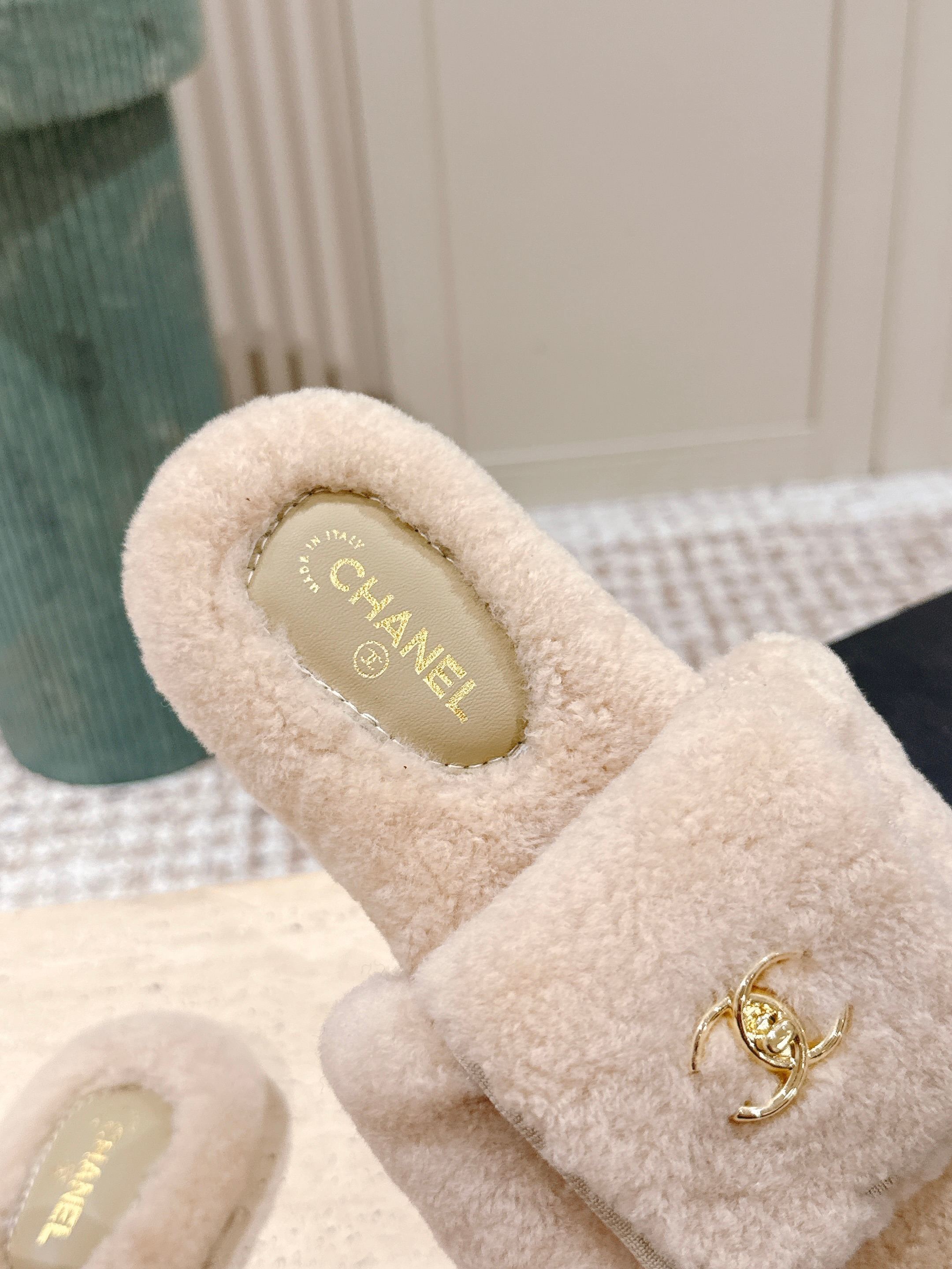 Luxury beige Chanel shearling slides with gold CC logo hardware on a display stand - Hình 7