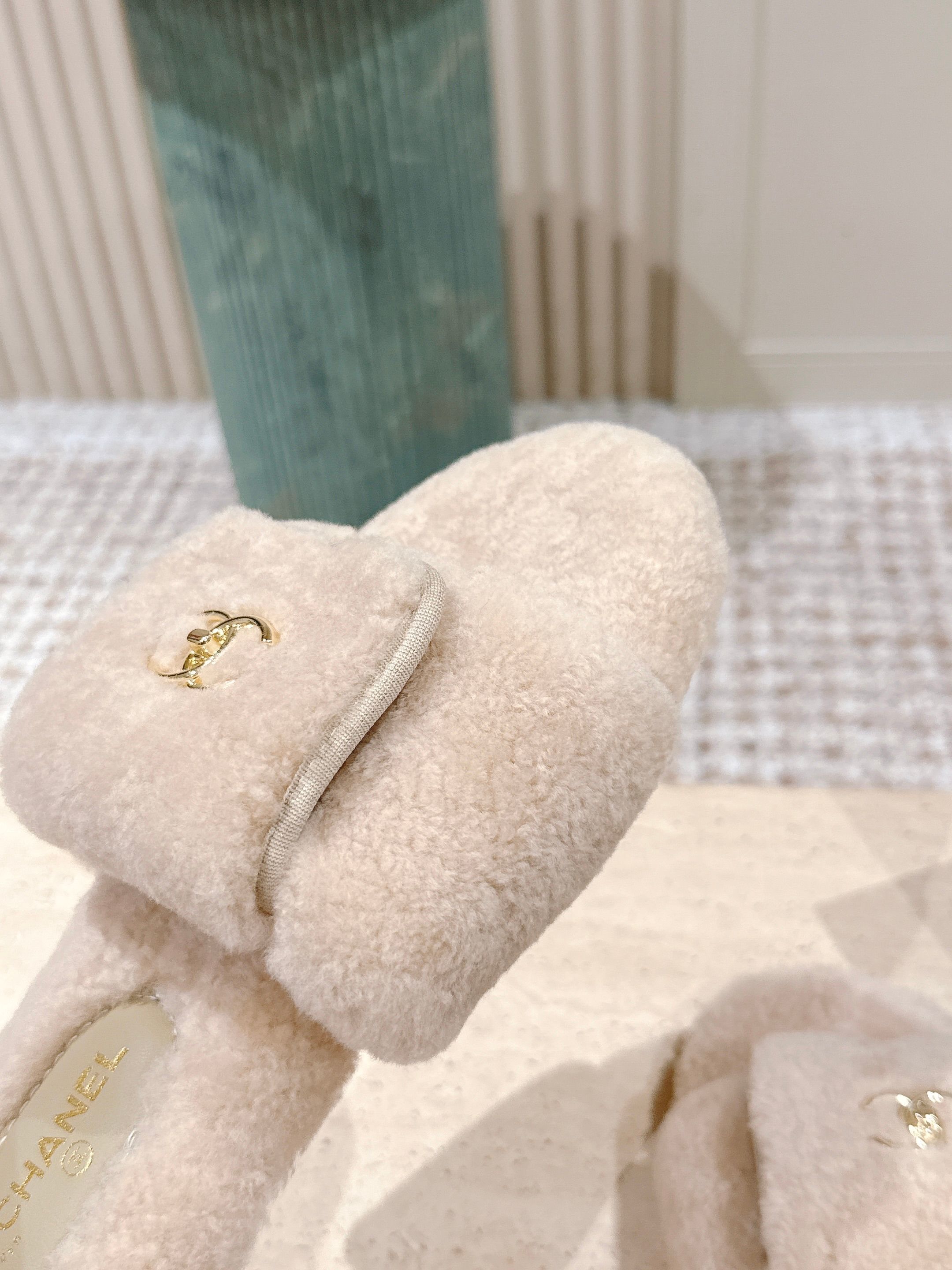 Luxury beige Chanel shearling slides with gold CC logo hardware on a display stand - Hình 6