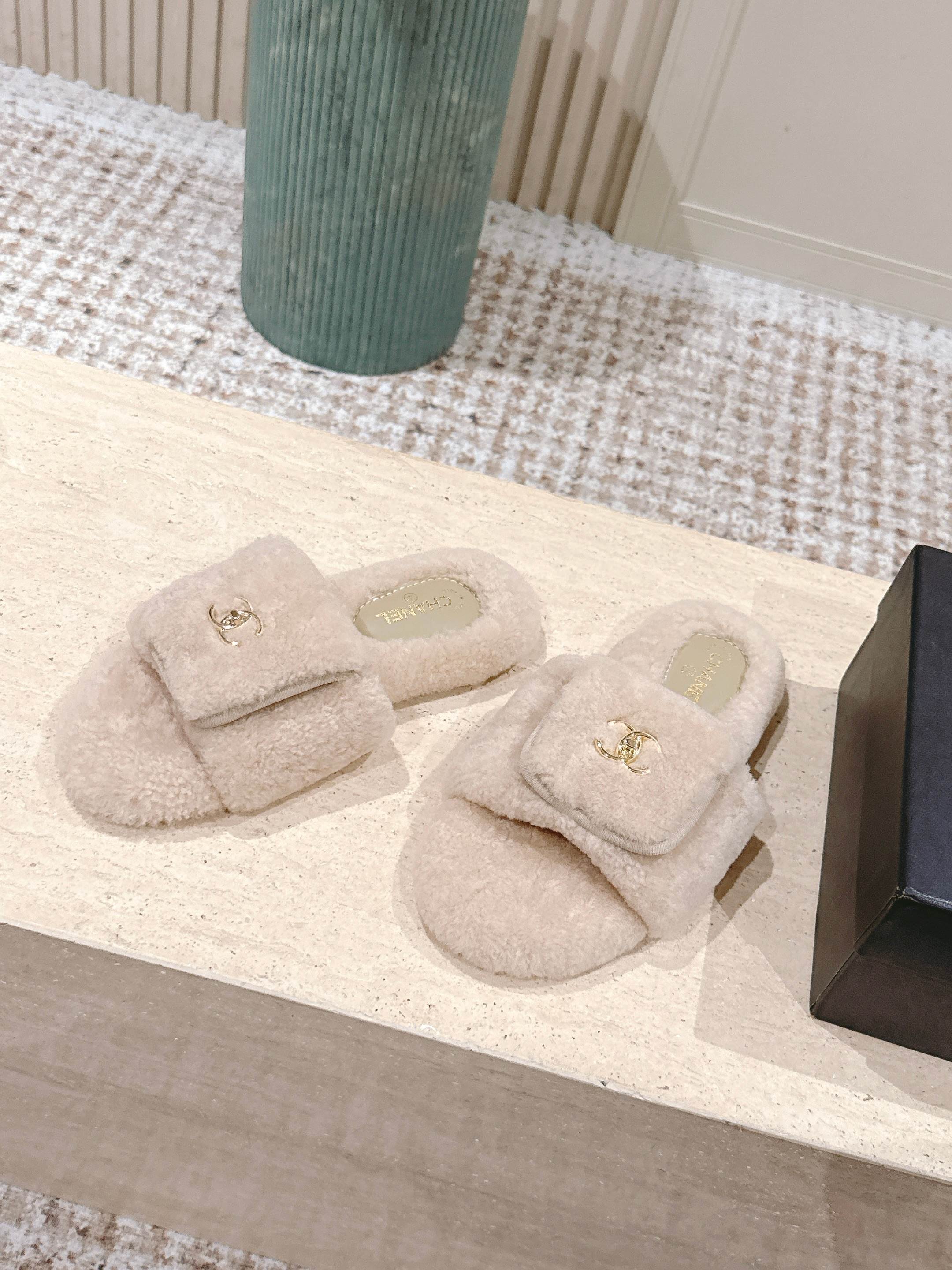 Luxury beige Chanel shearling slides with gold CC logo hardware on a display stand - Hình 3