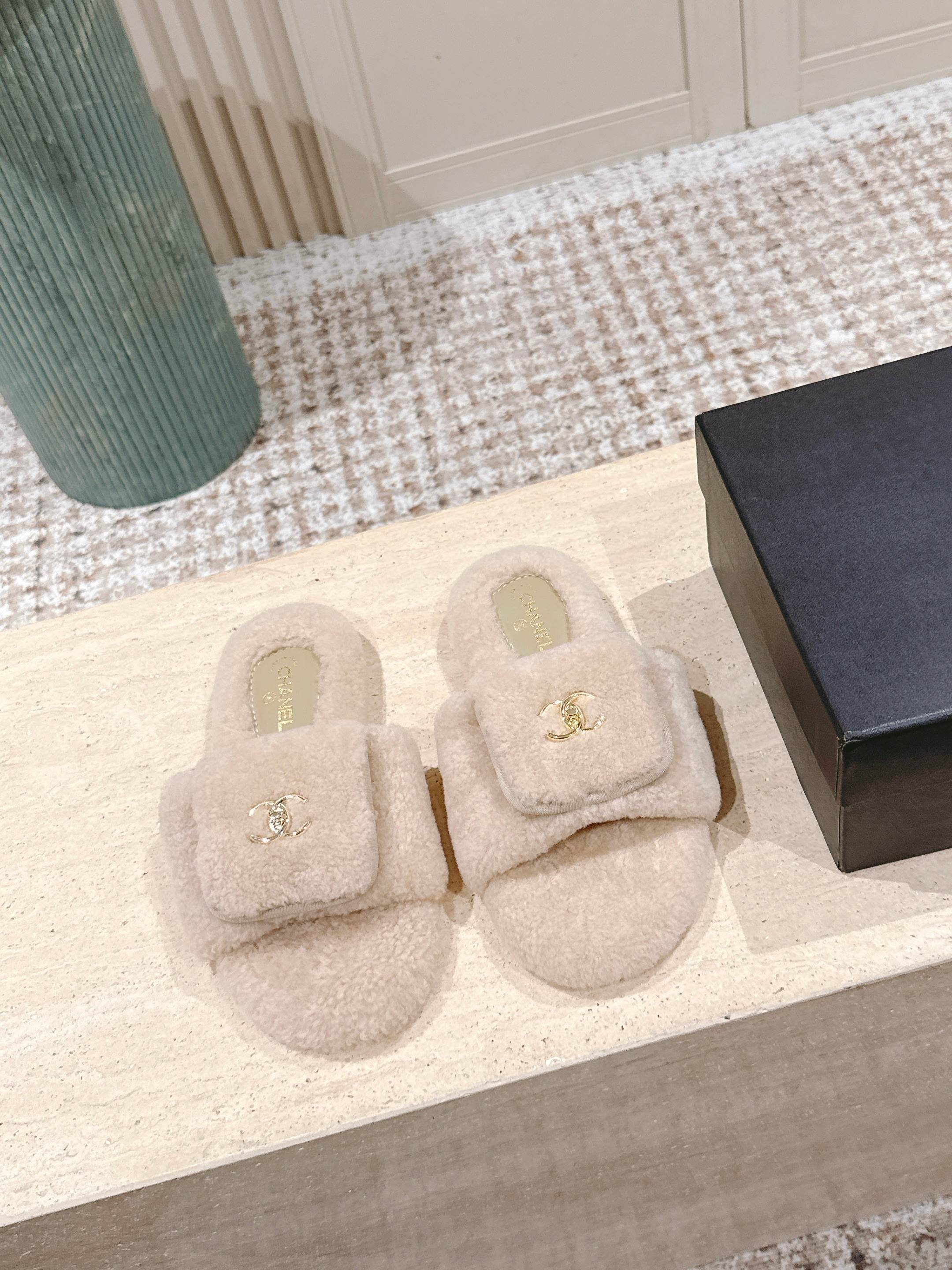 Luxury beige Chanel shearling slides with gold CC logo hardware on a display stand - Hình 2