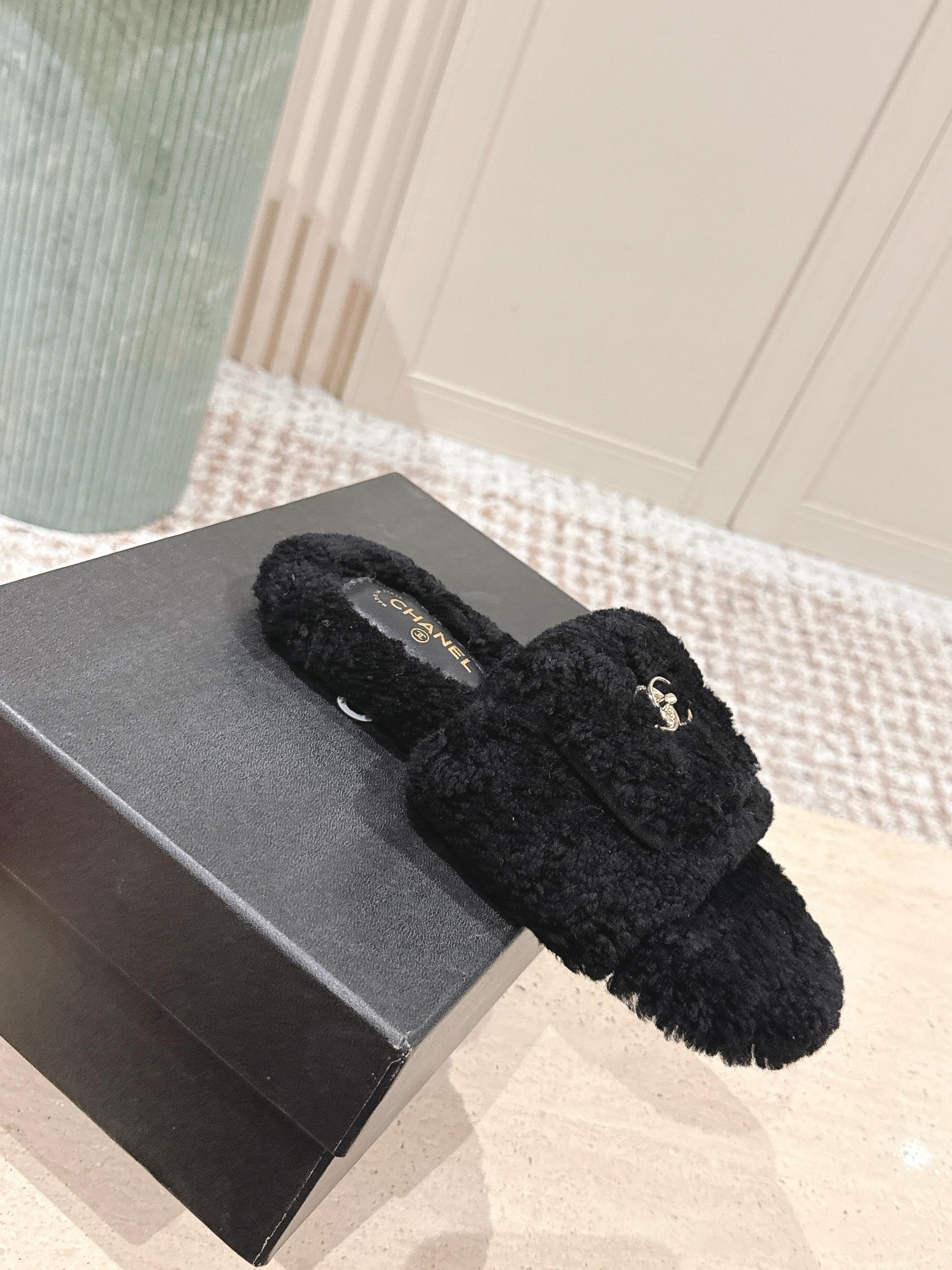 A pair of luxury black fuzzy Chanel shearling slides featuring silver interlocking CC logos on the wide straps. - Hình 4