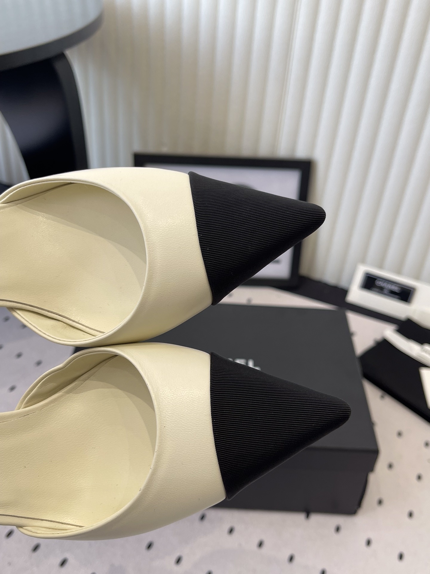 Luxury Chanel cream pumps with black pointed toes, featuring a pearl ankle strap and a black camellia flower detail with CC logo. - Hình 4