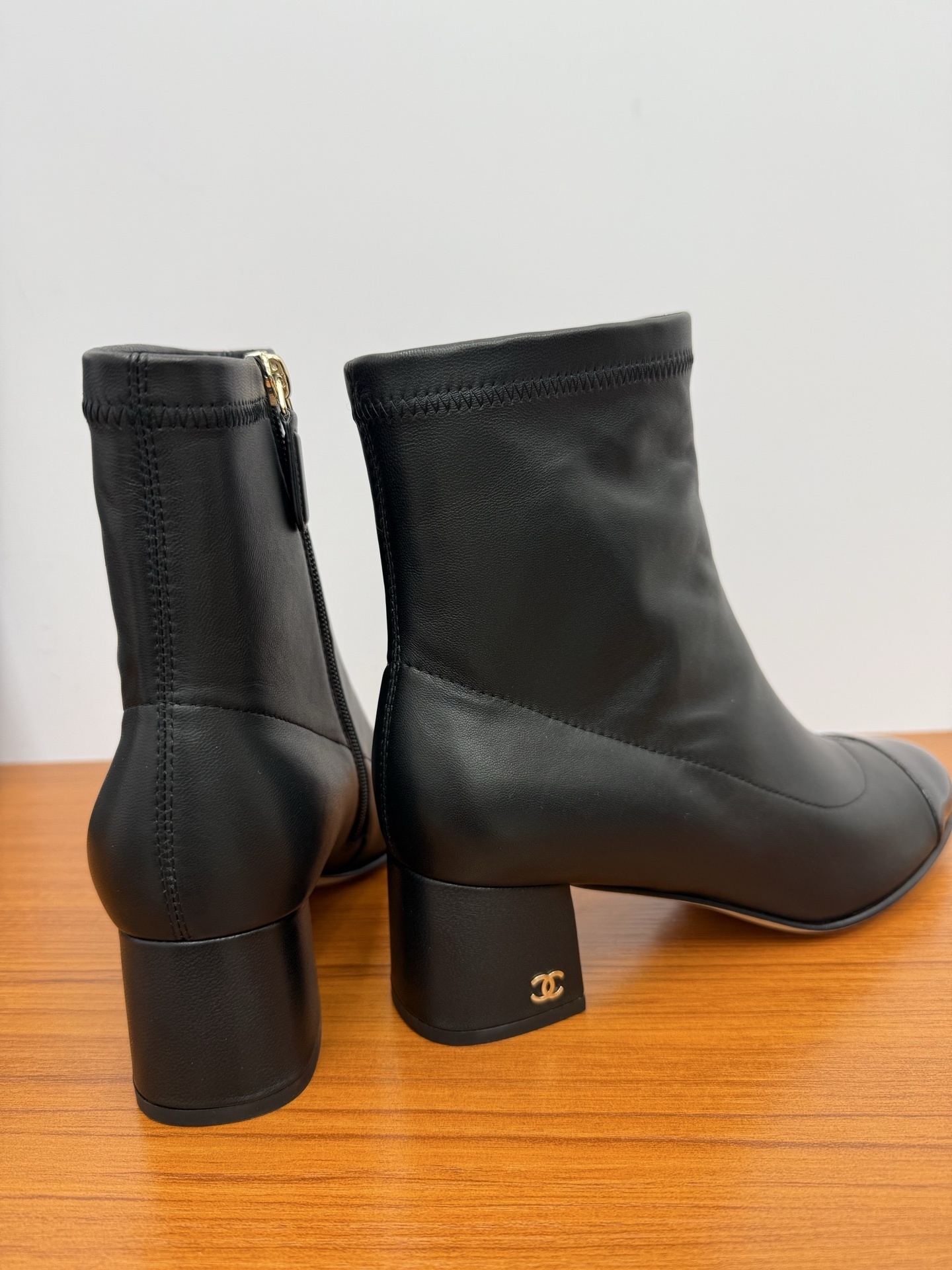 Front and side view of Chanel black leather ankle boots with glossy patent leather toe caps and gold CC logo on block heels. - Hình 8