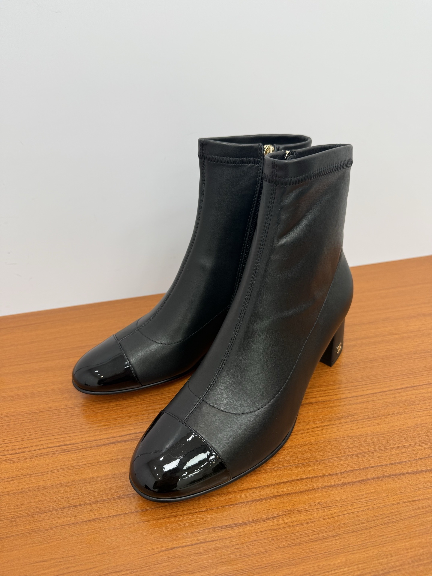 Front and side view of Chanel black leather ankle boots with glossy patent leather toe caps and gold CC logo on block heels. - Hình 3