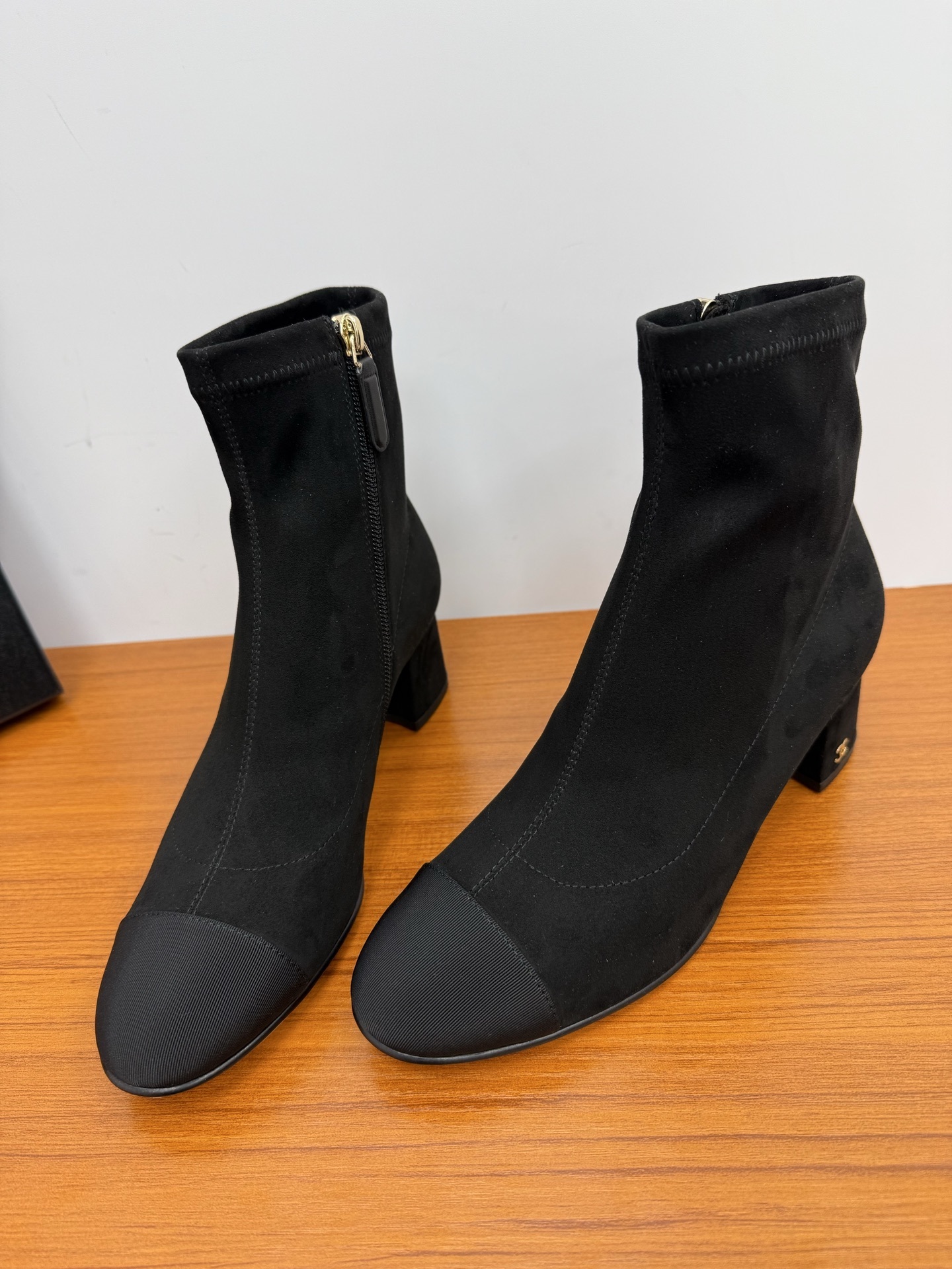 A pair of black Chanel suede sock boots with a ribbed cap-toe design and gold-tone CC logo on the heel. - Hình 5