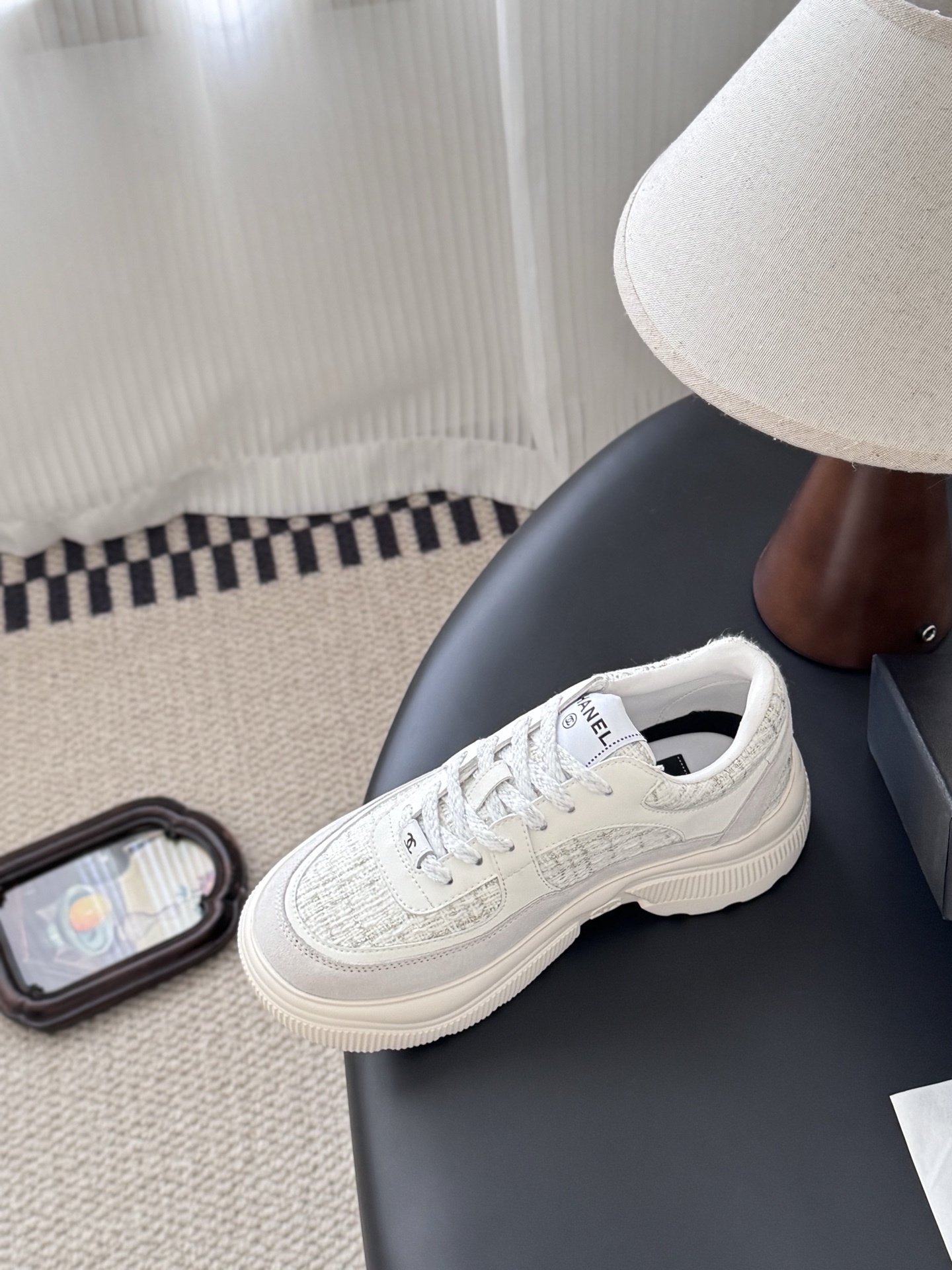 A pair of white Chanel sneakers featuring tweed panels and leather overlays presented next to an original black Chanel brand box. - Hình 6