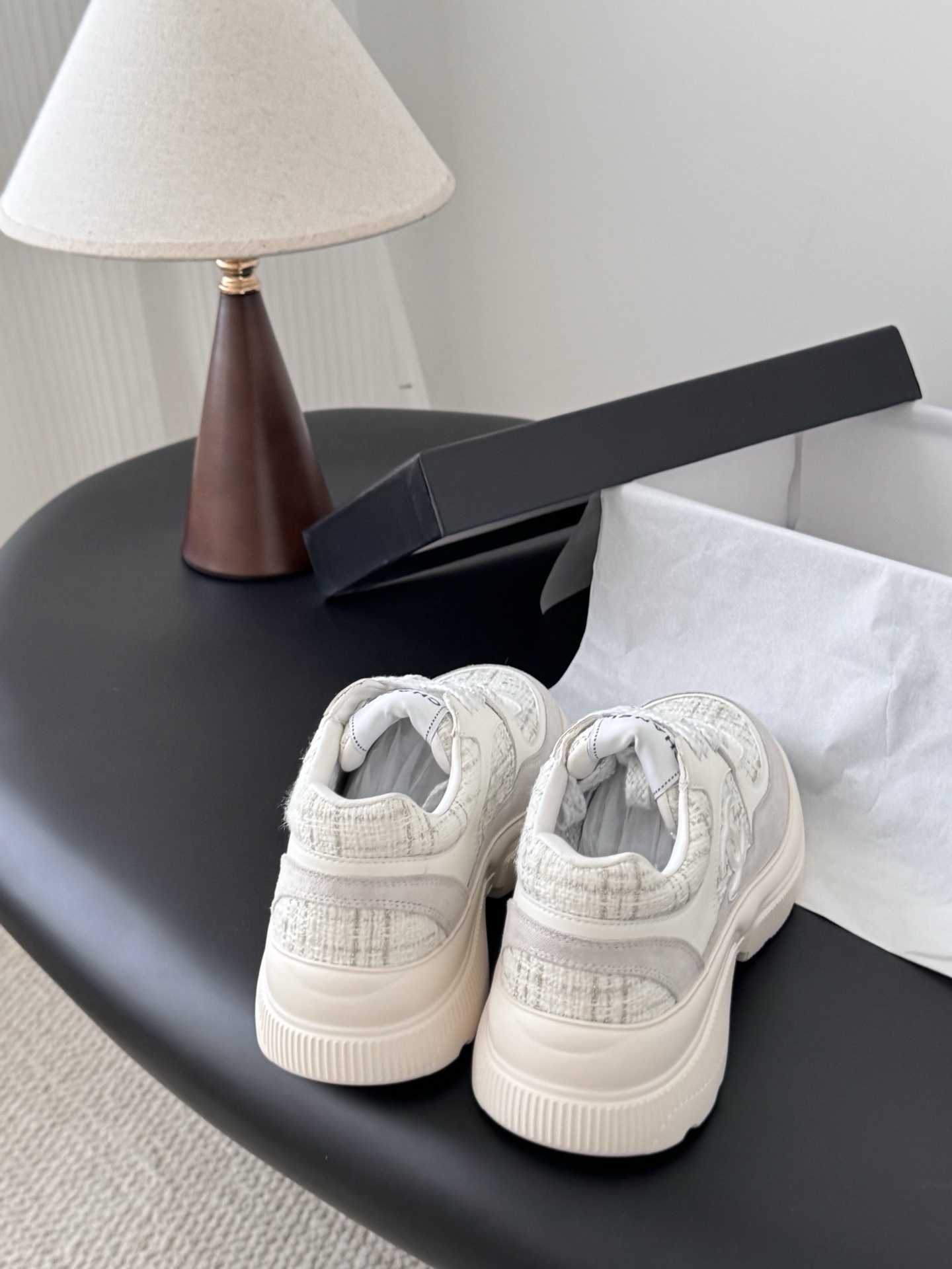 A pair of white Chanel sneakers featuring tweed panels and leather overlays presented next to an original black Chanel brand box. - Hình 3