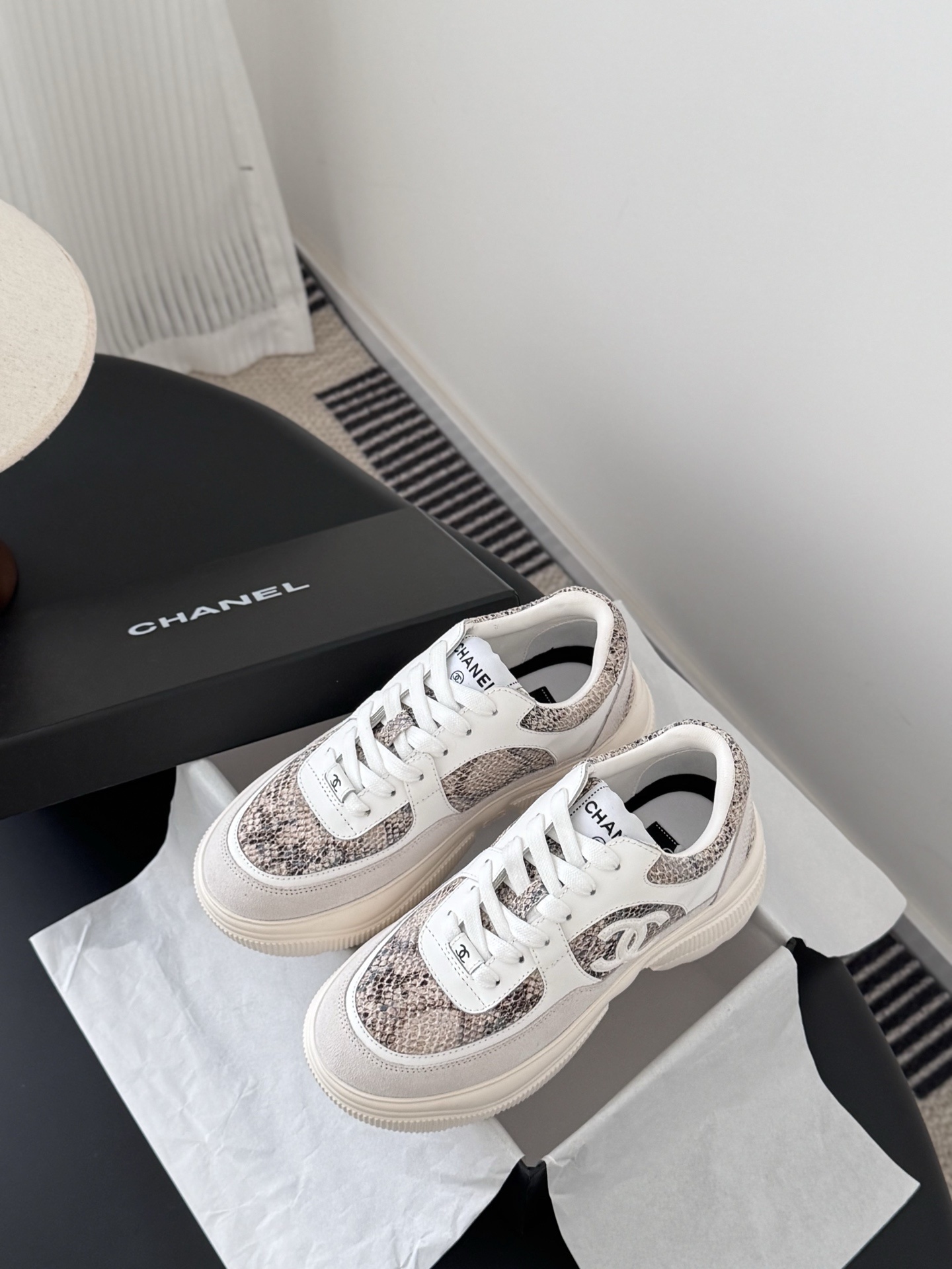 Pair of Chanel chunky sneakers with white leather and snakeskin print accents next to a black Chanel box. - Hình 6
