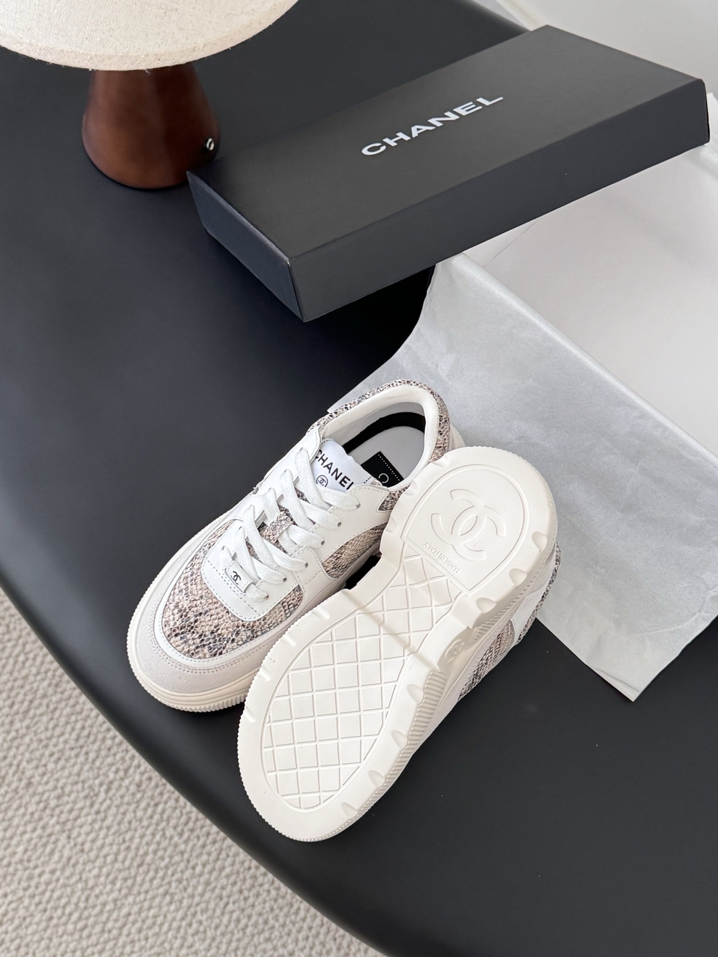 Pair of Chanel chunky sneakers with white leather and snakeskin print accents next to a black Chanel box. - Hình 5