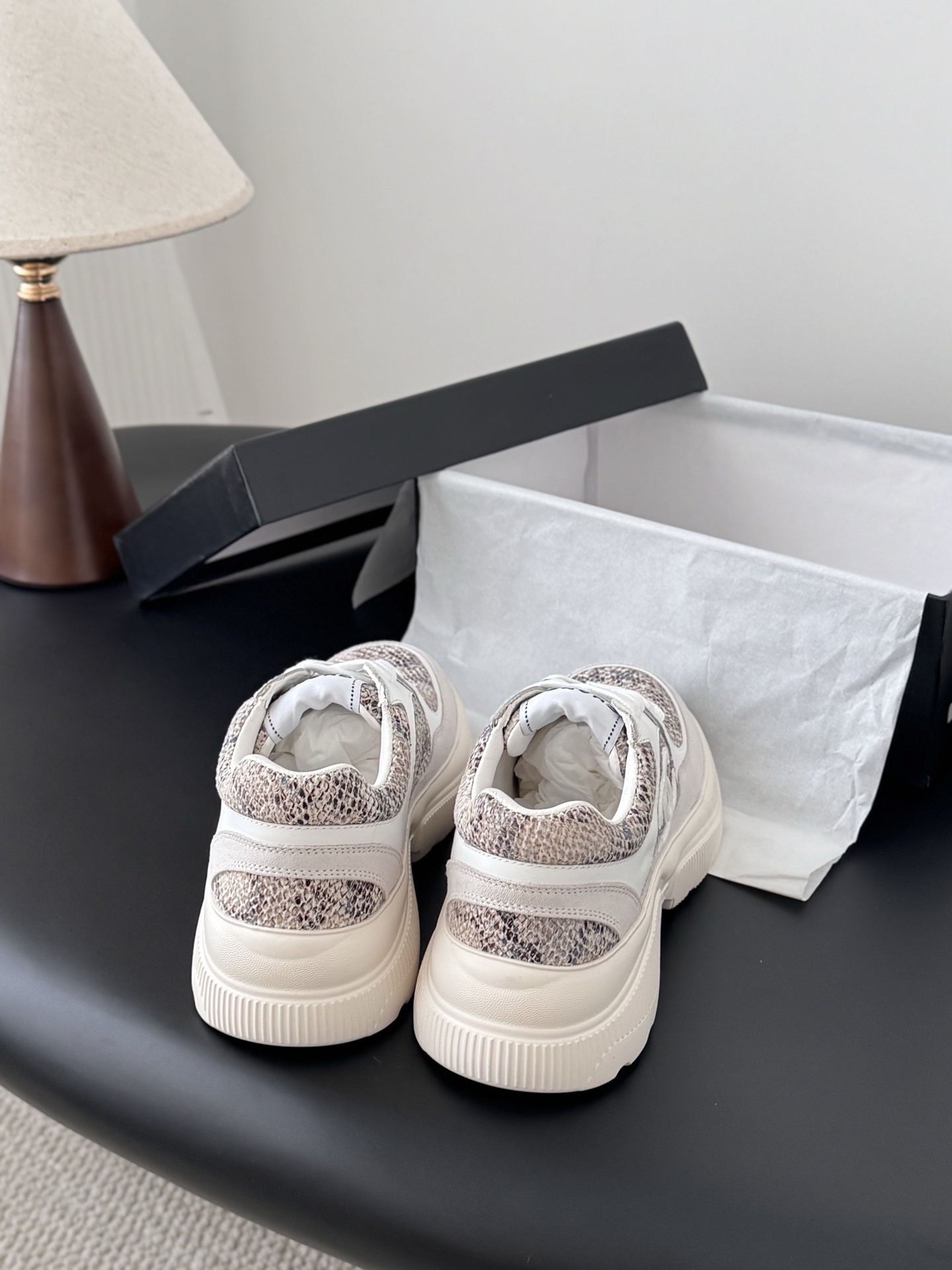 Pair of Chanel chunky sneakers with white leather and snakeskin print accents next to a black Chanel box. - Hình 3