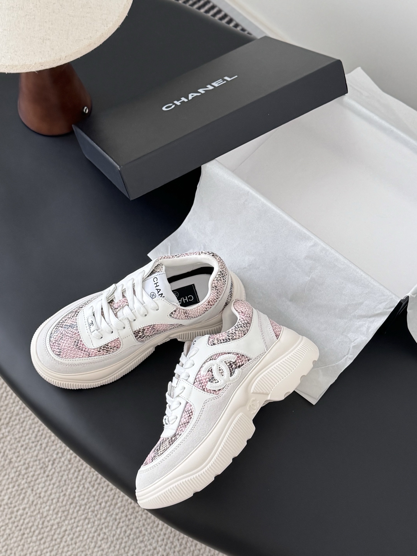 Chanel white leather sneakers with pink python print and chunky soles next to a black Chanel shoe box. - Hình 4