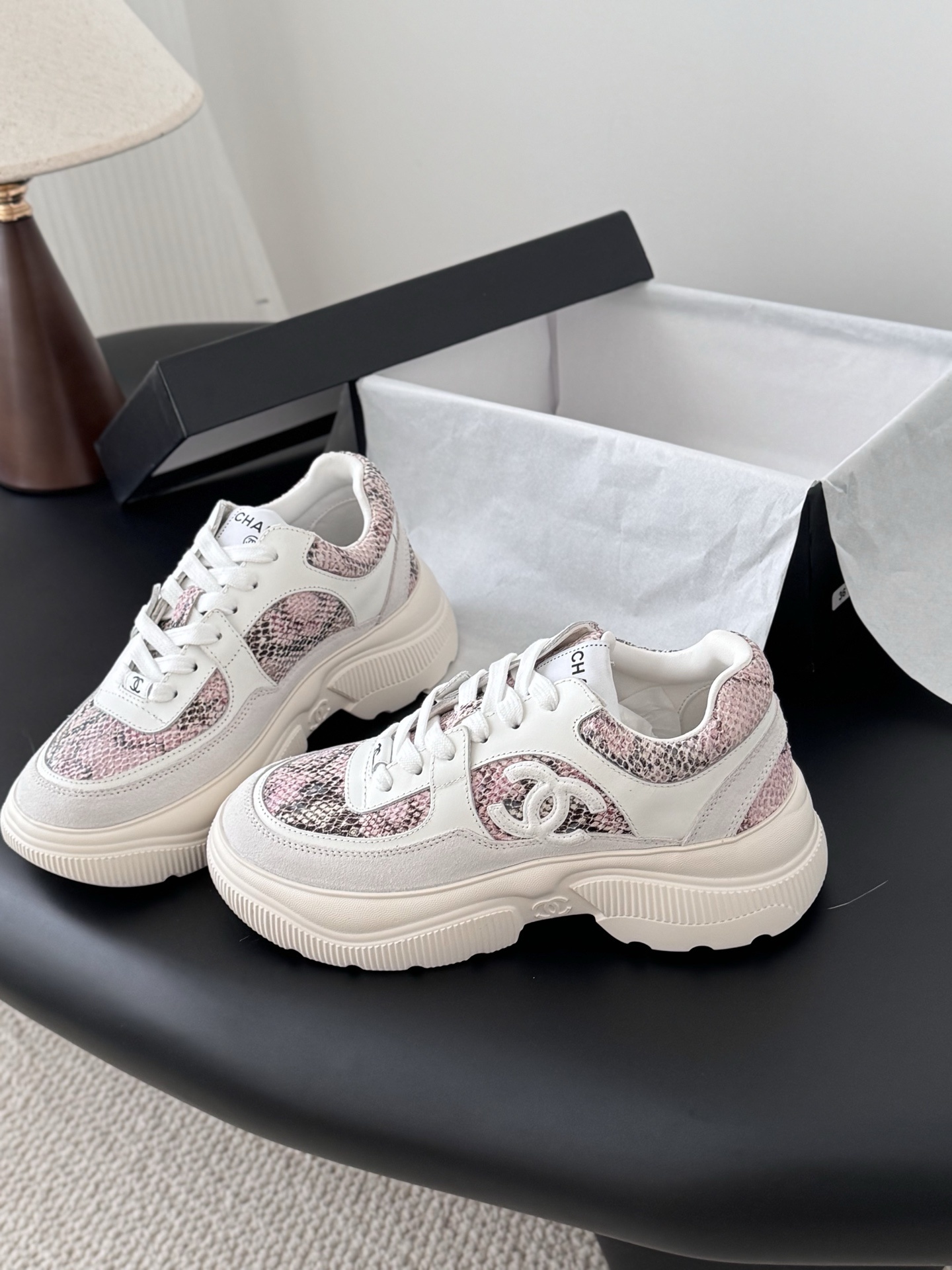 Chanel white leather sneakers with pink python print and chunky soles next to a black Chanel shoe box. - Hình 2