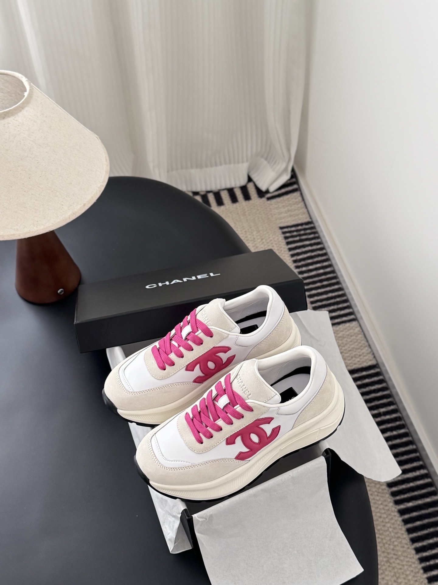 Pair of Chanel white and cream suede sneakers with hot pink laces and logo next to a black Chanel box - Hình 9
