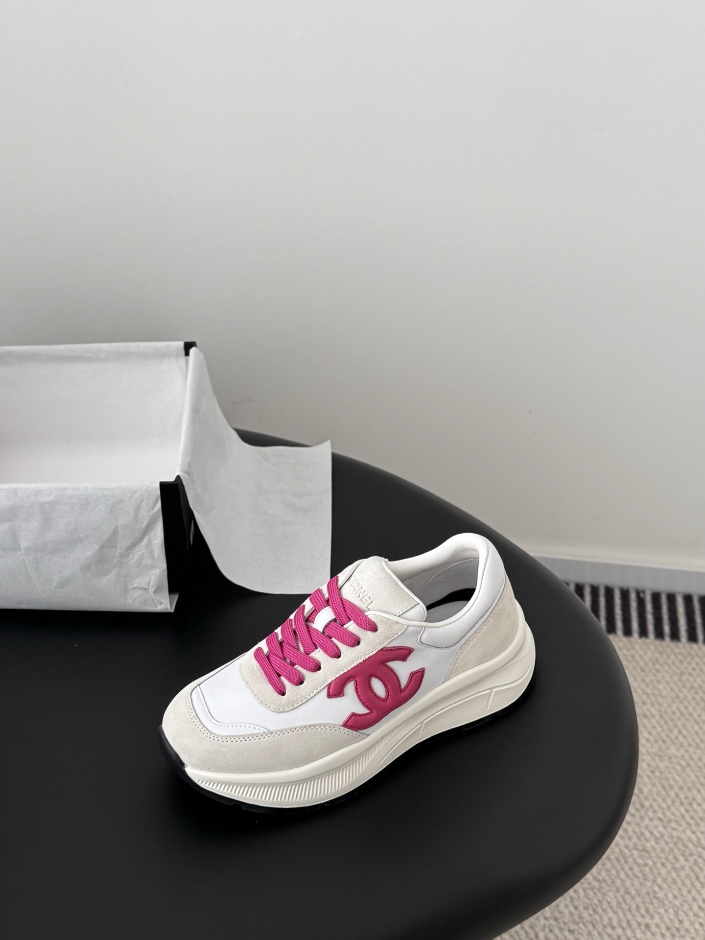 Pair of Chanel white and cream suede sneakers with hot pink laces and logo next to a black Chanel box - Hình 6
