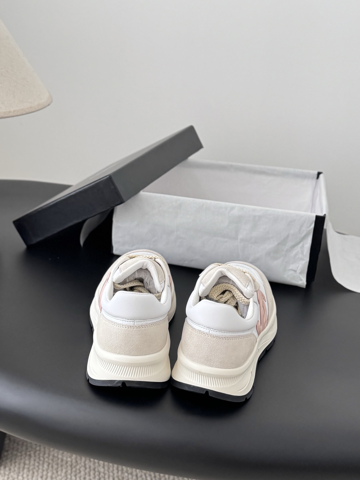 A pair of Chanel women's sneakers in white and beige suede with a pink CC logo, displayed next to a black Chanel shoe box. - Hình 7