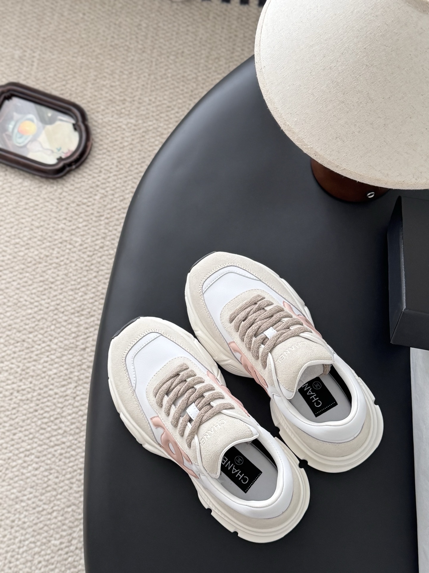 A pair of Chanel white and pink leather sneakers with chunky soles next to a black Chanel shoebox - Hình 8