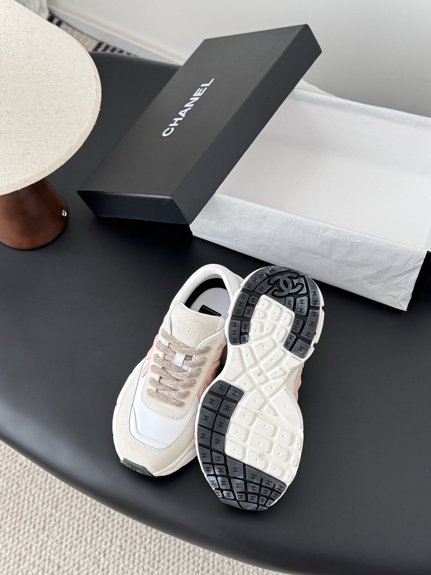 A pair of Chanel white and pink leather sneakers with chunky soles next to a black Chanel shoebox - Hình 4
