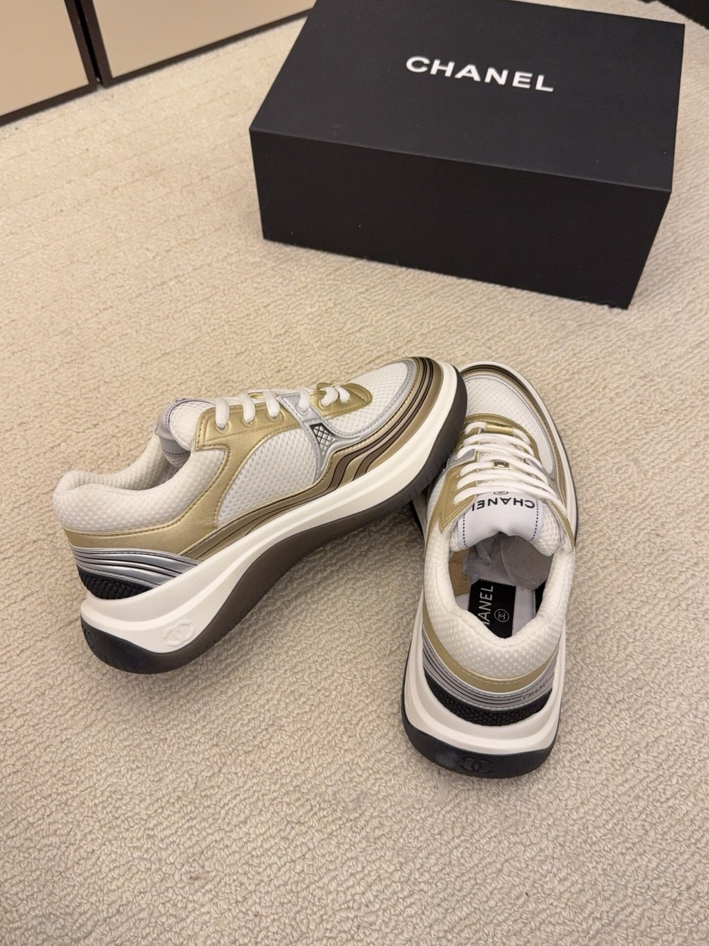 Two pairs of Chanel metallic mesh sneakers in silver and gold colorways displayed on a black Chanel box. - Hình 9