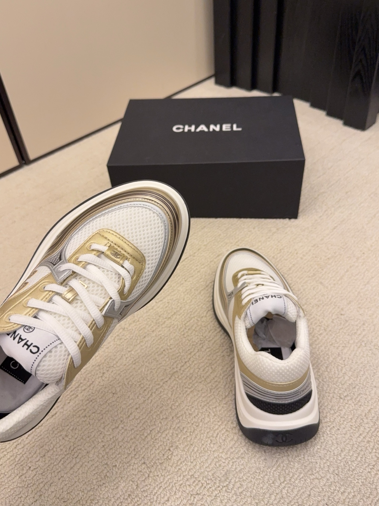 Two pairs of Chanel metallic mesh sneakers in silver and gold colorways displayed on a black Chanel box. - Hình 8