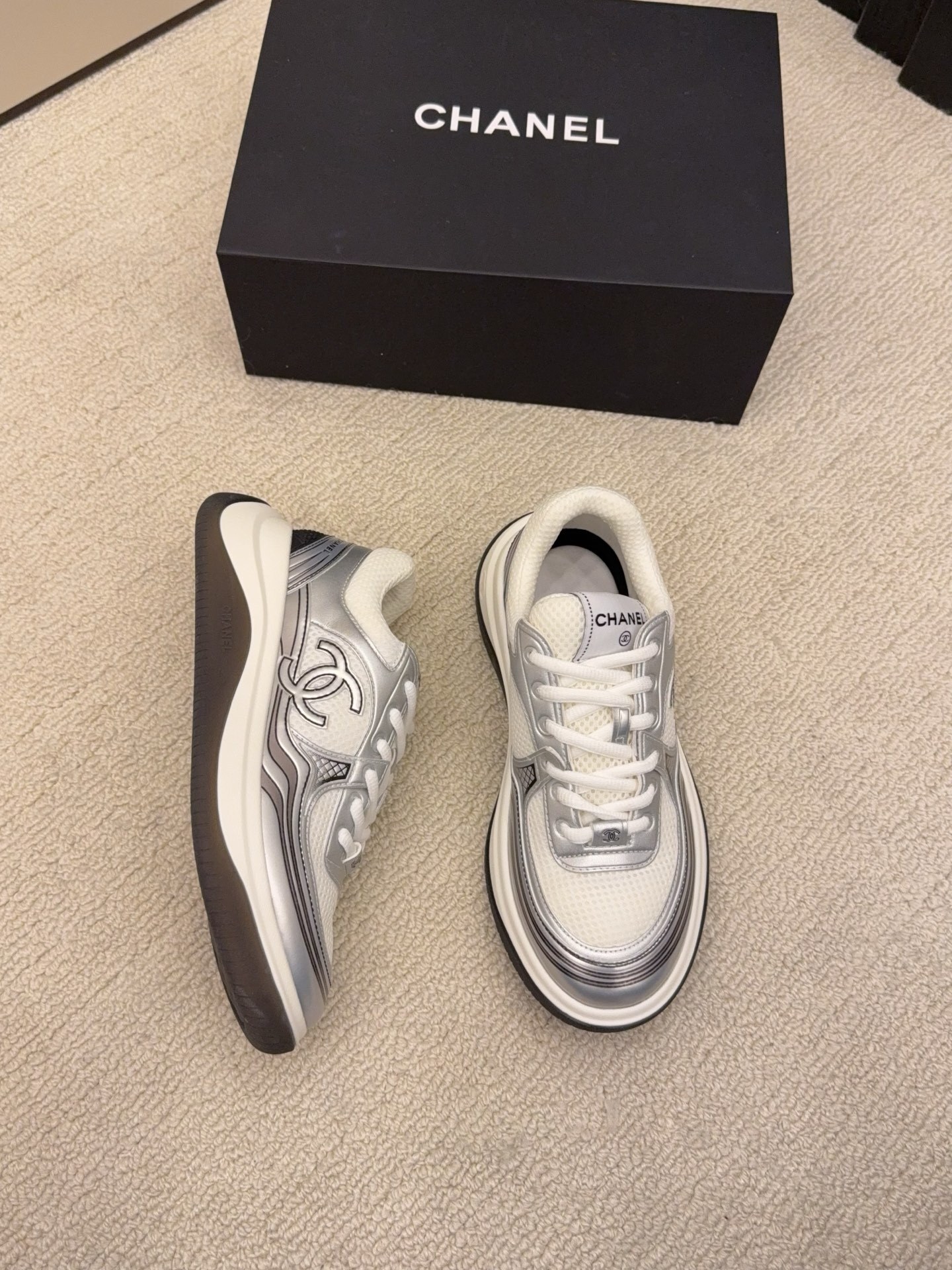 Two pairs of Chanel metallic mesh sneakers in silver and gold colorways displayed on a black Chanel box. - Hình 3