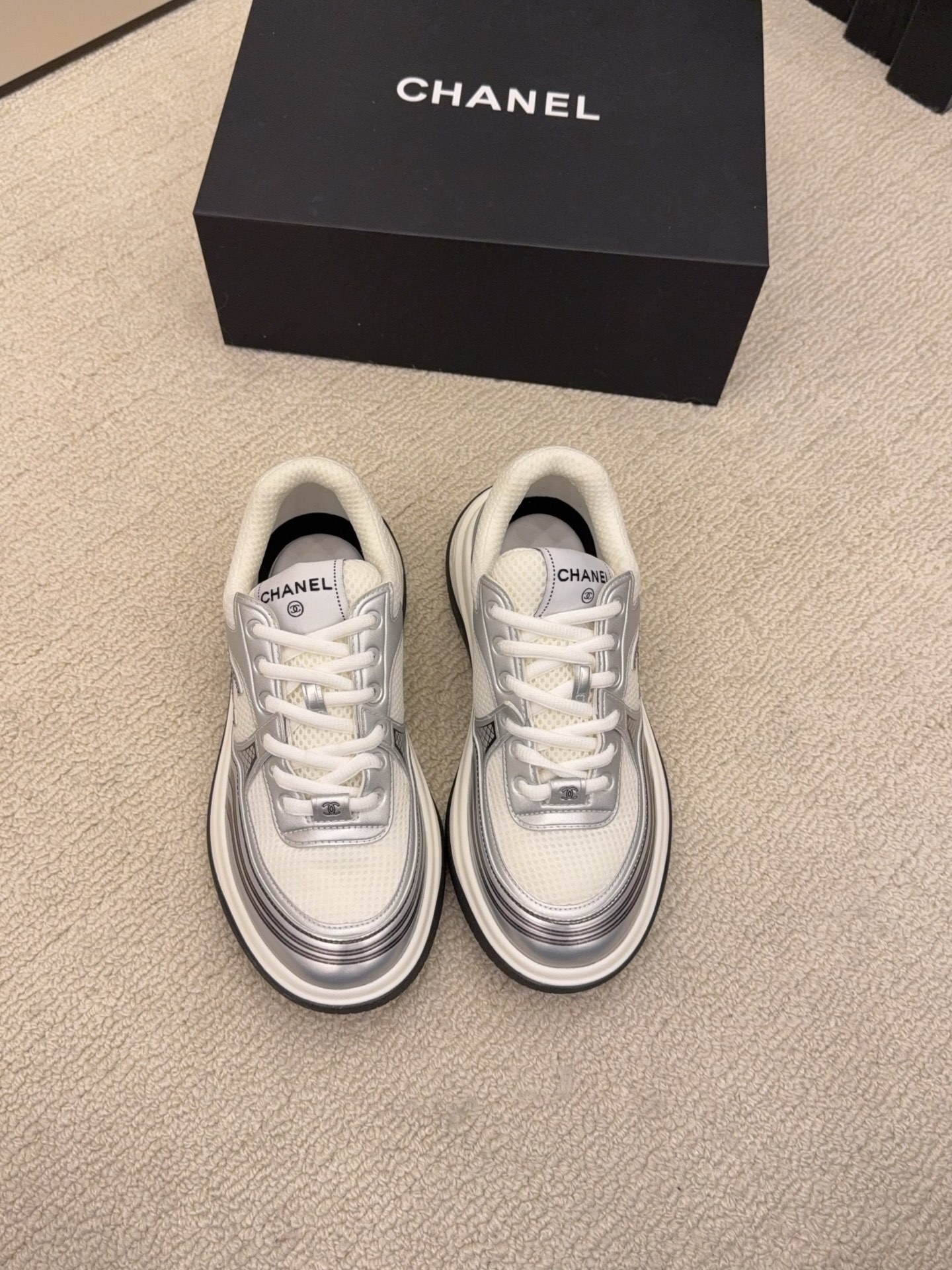 Two pairs of Chanel metallic mesh sneakers in silver and gold colorways displayed on a black Chanel box. - Hình 2