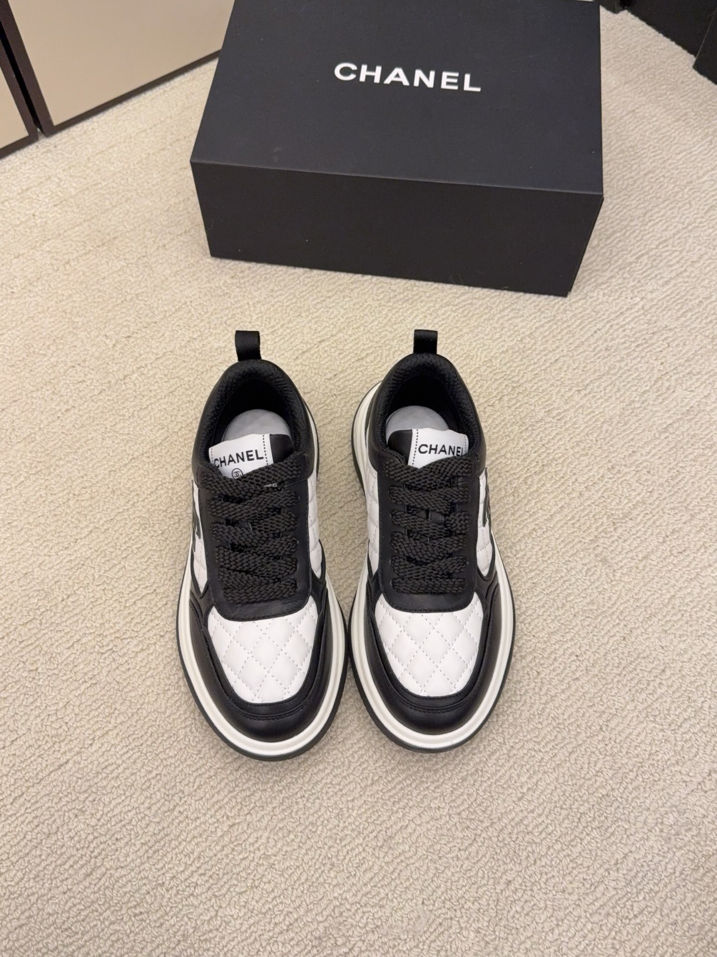 Chanel luxury quilted leather sneakers in black and white featuring the interlocking CC logo on the side. - Hình 2