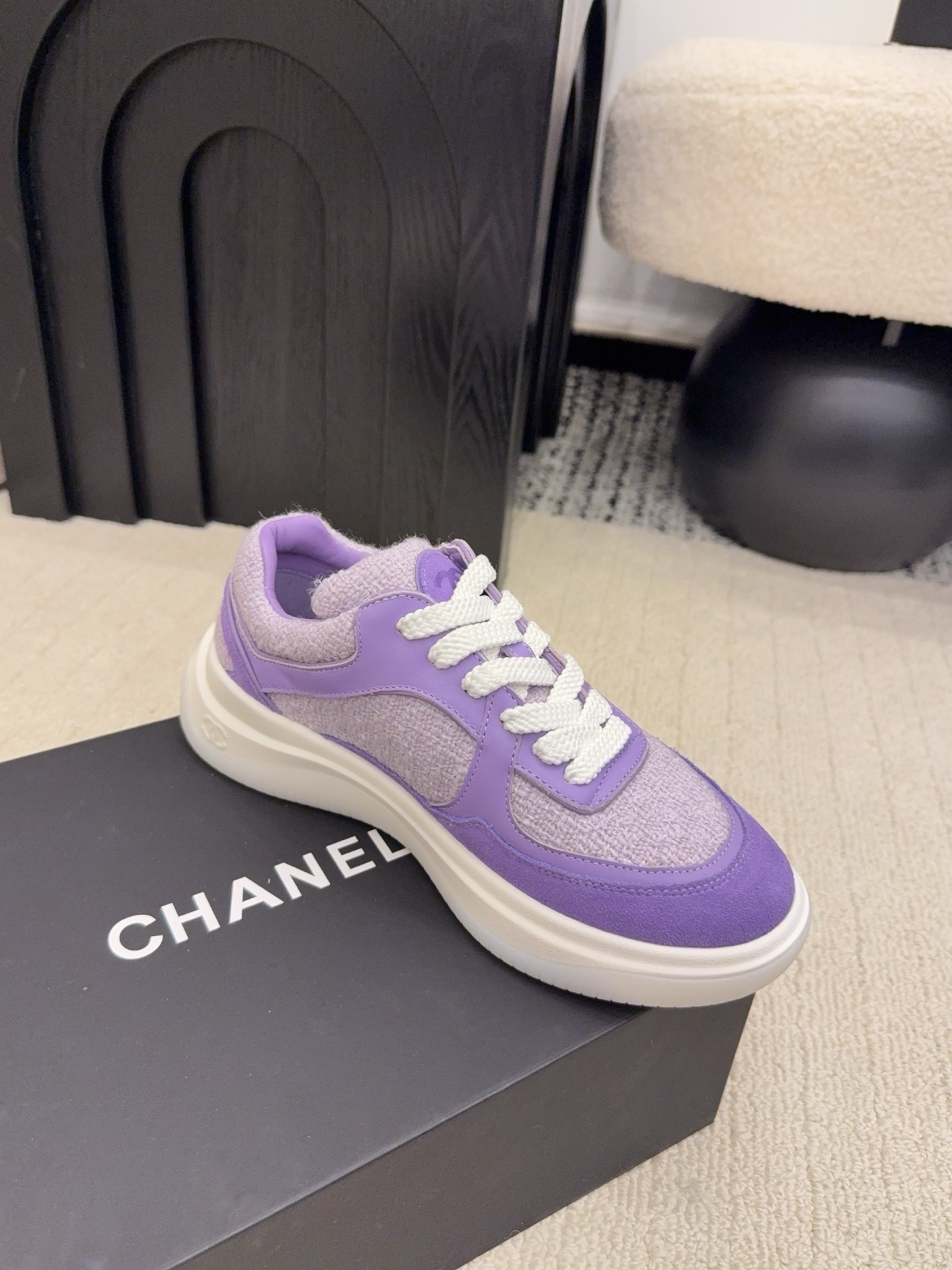 A pair of luxury Chanel purple tweed and suede sneakers with white chunky soles and white laces placed on a black designer shoe box. - Hình 5