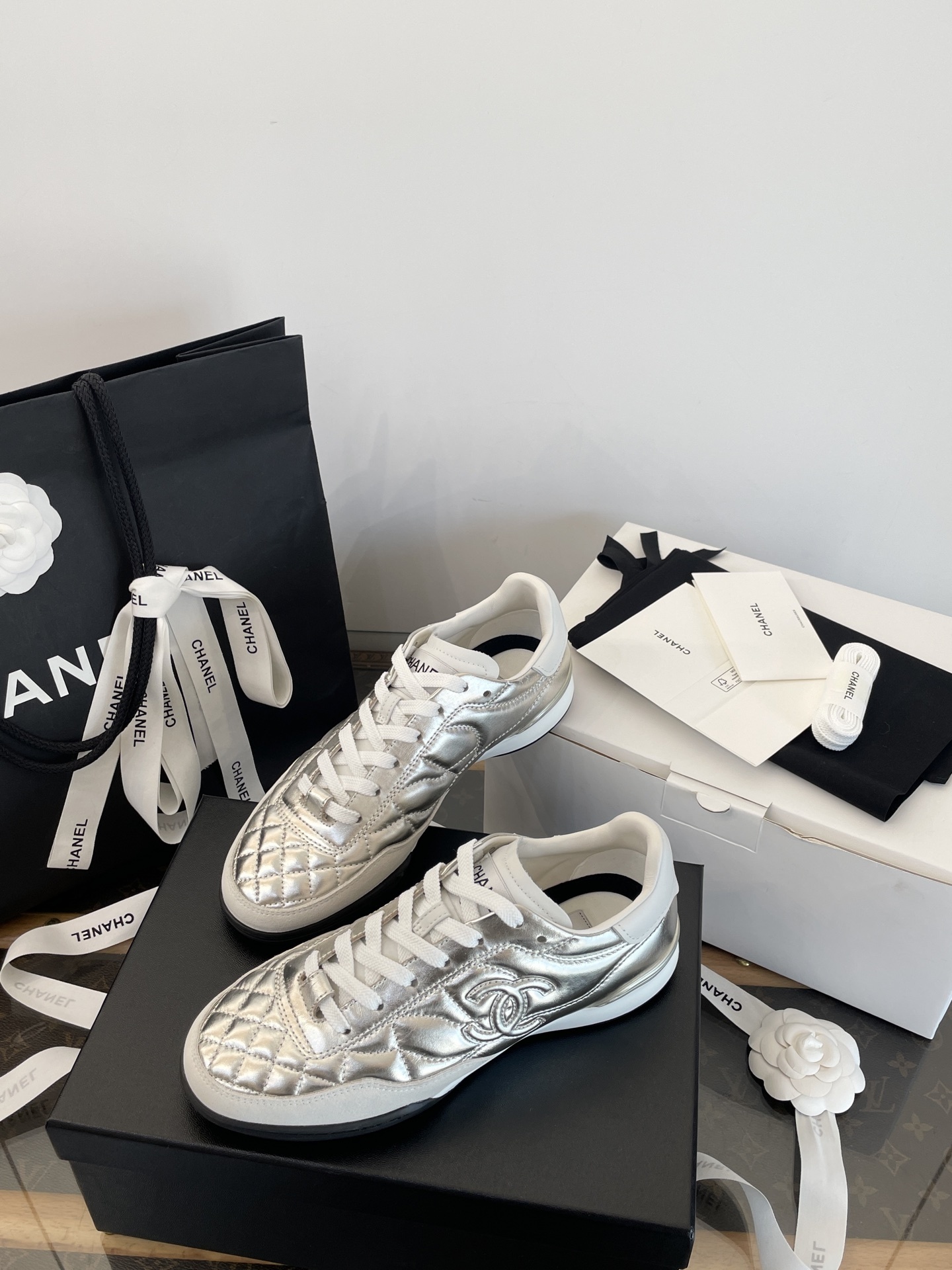 A pair of Chanel metallic silver quilted leather sneakers with CC logo, presented with original black shopping bag and white box. - Hình 7