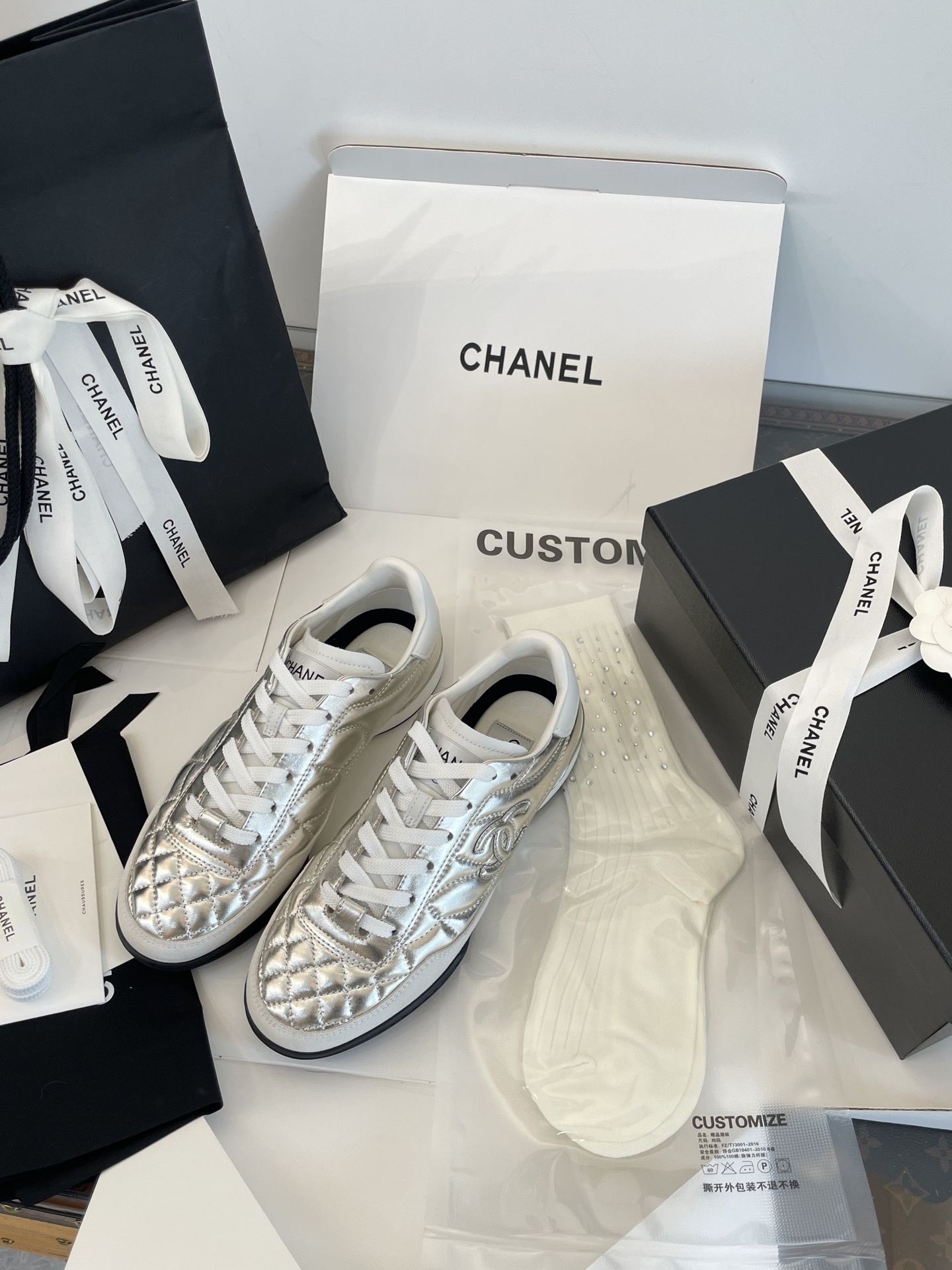 A pair of Chanel metallic silver quilted leather sneakers with CC logo, presented with original black shopping bag and white box. - Hình 6