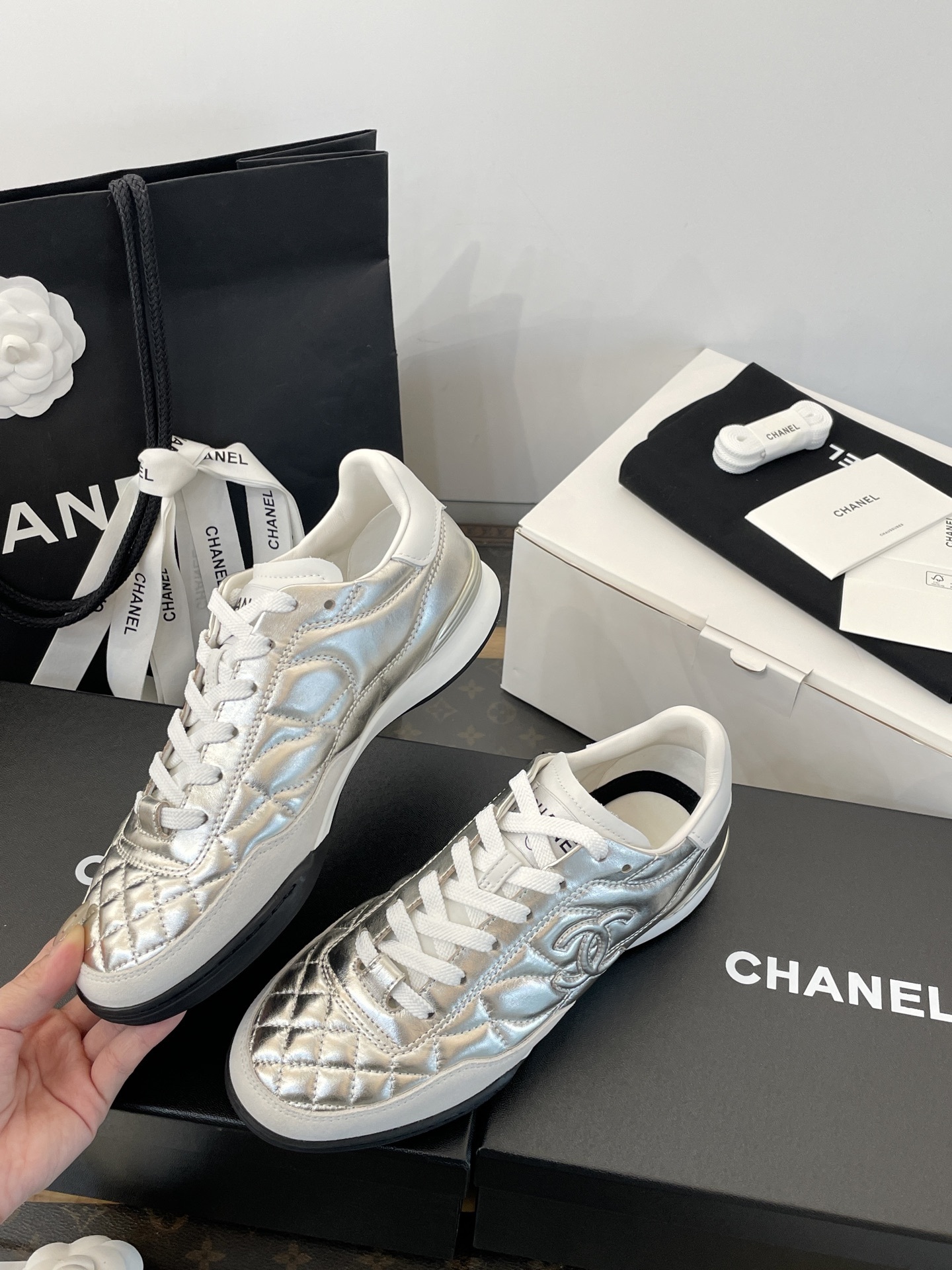 A pair of Chanel metallic silver quilted leather sneakers with CC logo, presented with original black shopping bag and white box. - Hình 3