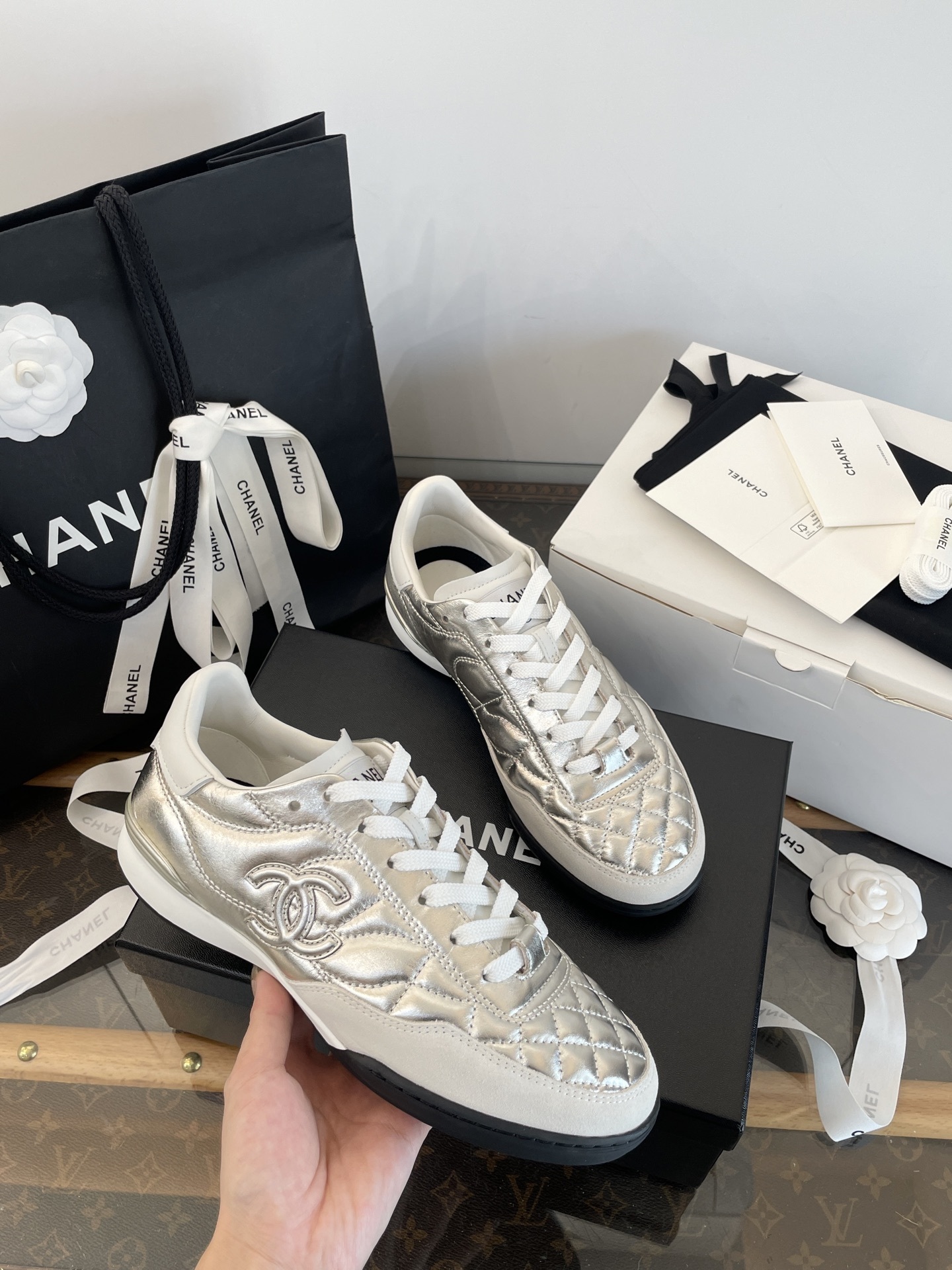 A pair of Chanel metallic silver quilted leather sneakers with CC logo, presented with original black shopping bag and white box. - Hình 2