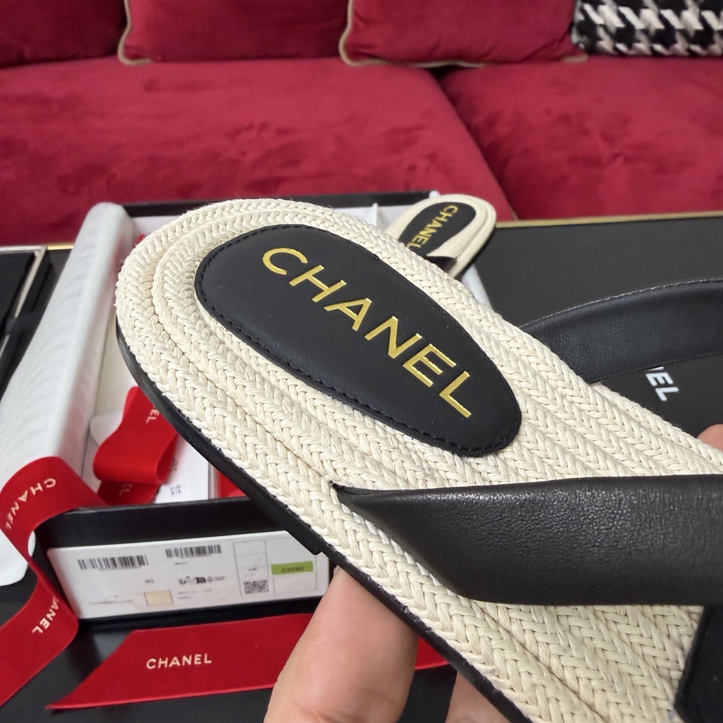 Close-up of Chanel black leather thong sandals with gold CC logo hardware and beige woven soles in a luxury box. - Hình 7