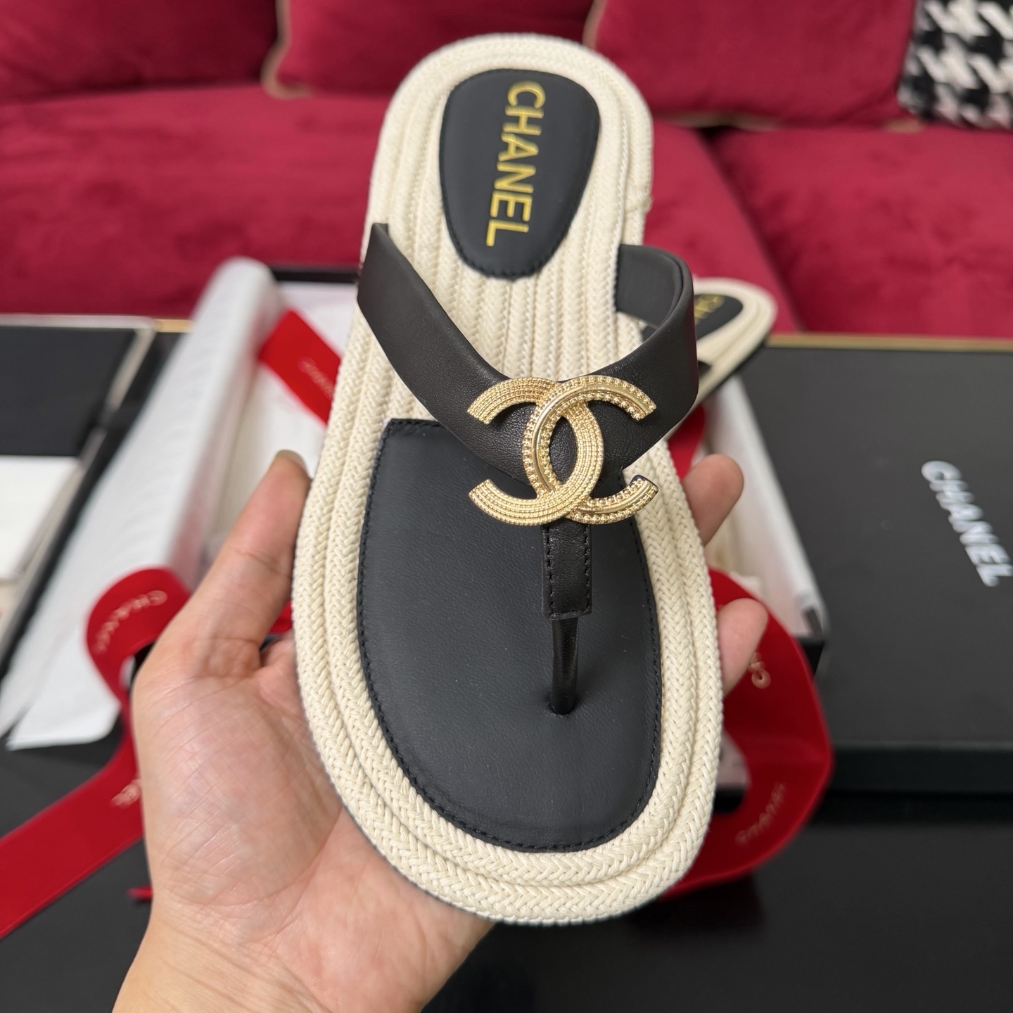 Close-up of Chanel black leather thong sandals with gold CC logo hardware and beige woven soles in a luxury box. - Hình 3