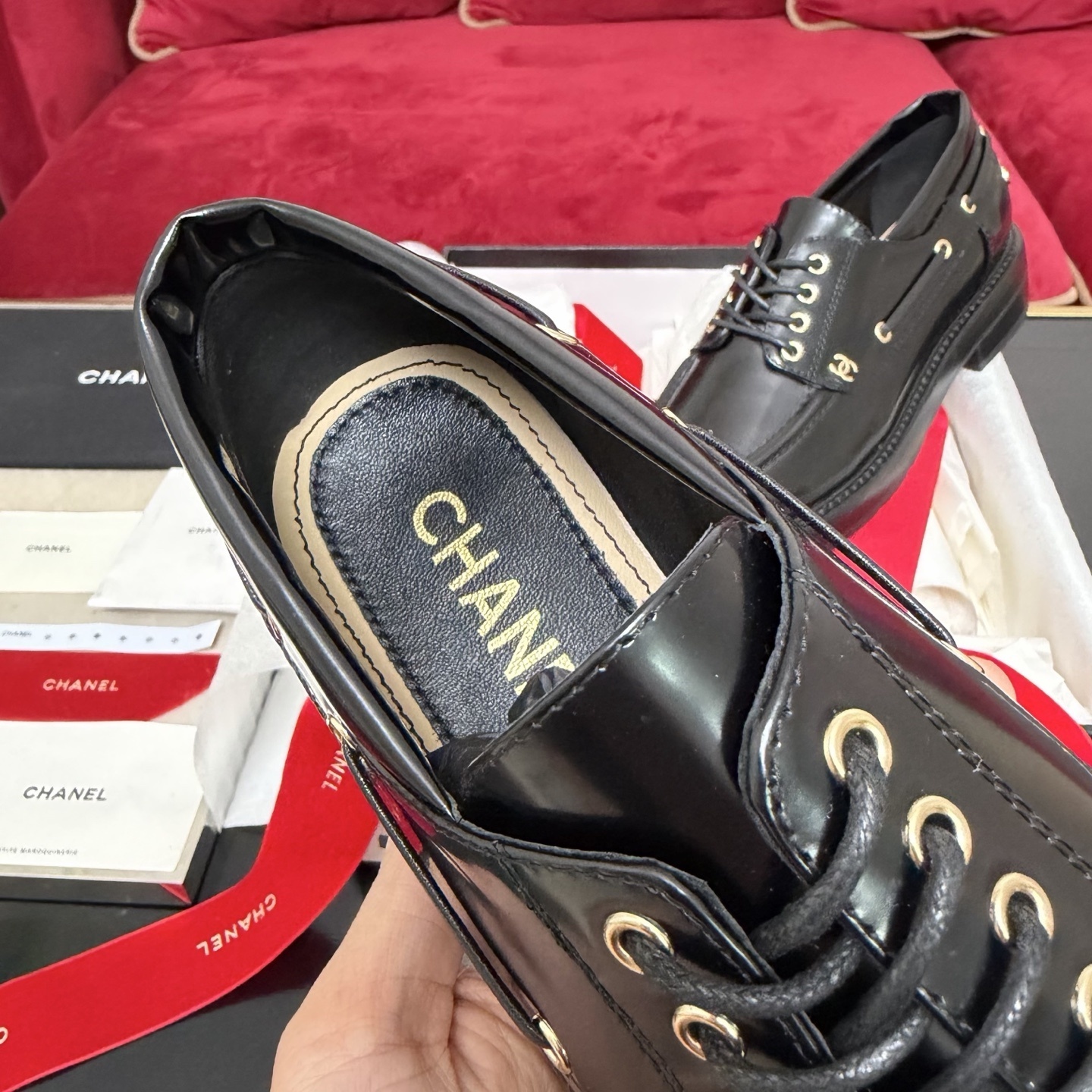 A pair of Chanel black leather lace-up loafers with gold CC logo hardware, displayed in a box with red velvet ribbons. - Hình 8