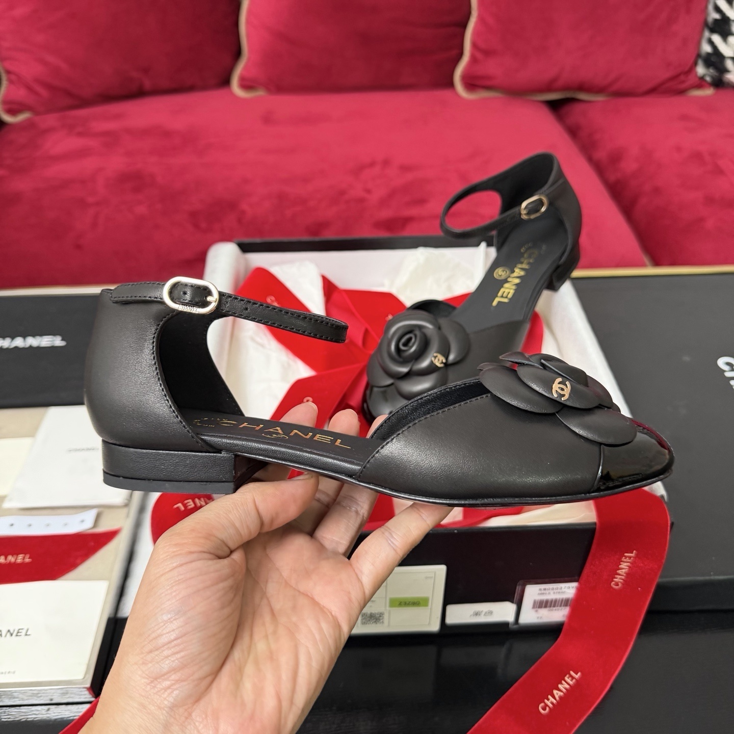 Pair of black Chanel ankle strap flats featuring a large camellia flower and patent leather toe cap in a luxury gift box. - Hình 5