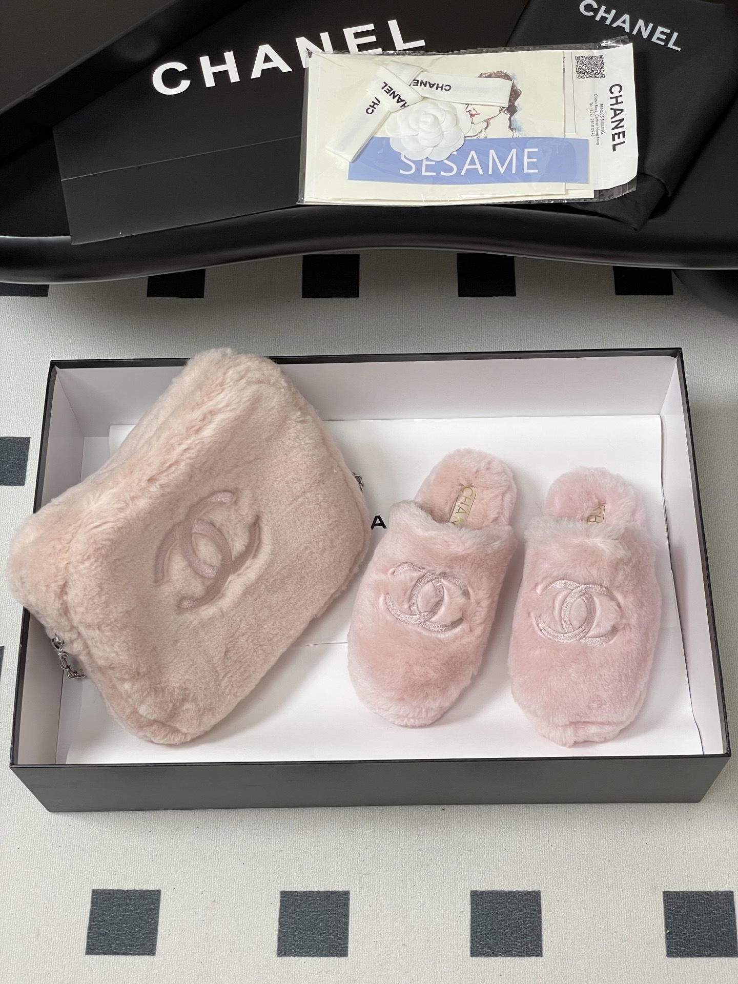A pair of soft pastel pink Chanel faux fur slippers featuring the embroidered interlocking CC logo on a black surface. - Hình 4