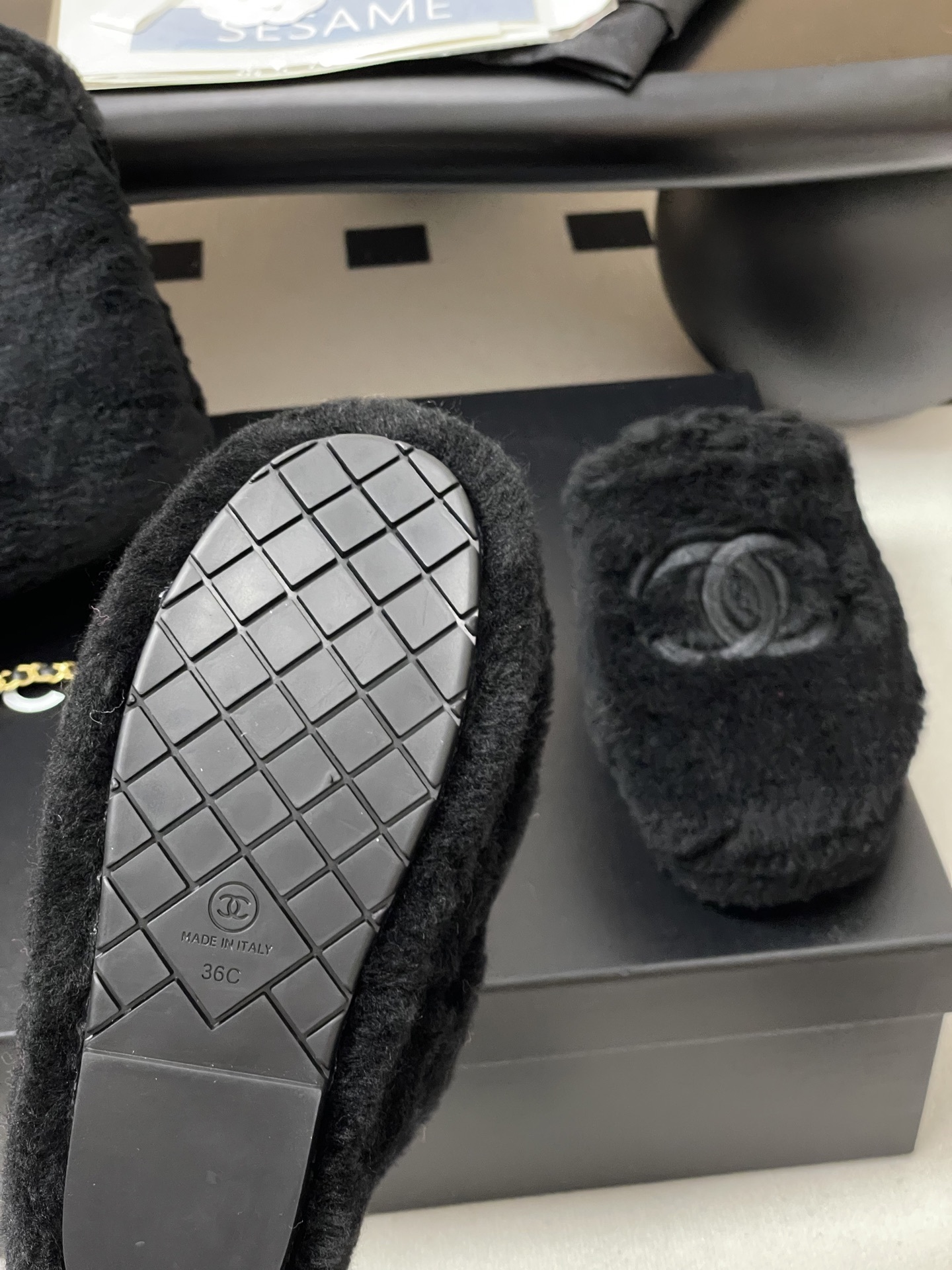 Pair of black plush fuzzy slippers with a grey interlocking CC logo on a black surface - Hình 7
