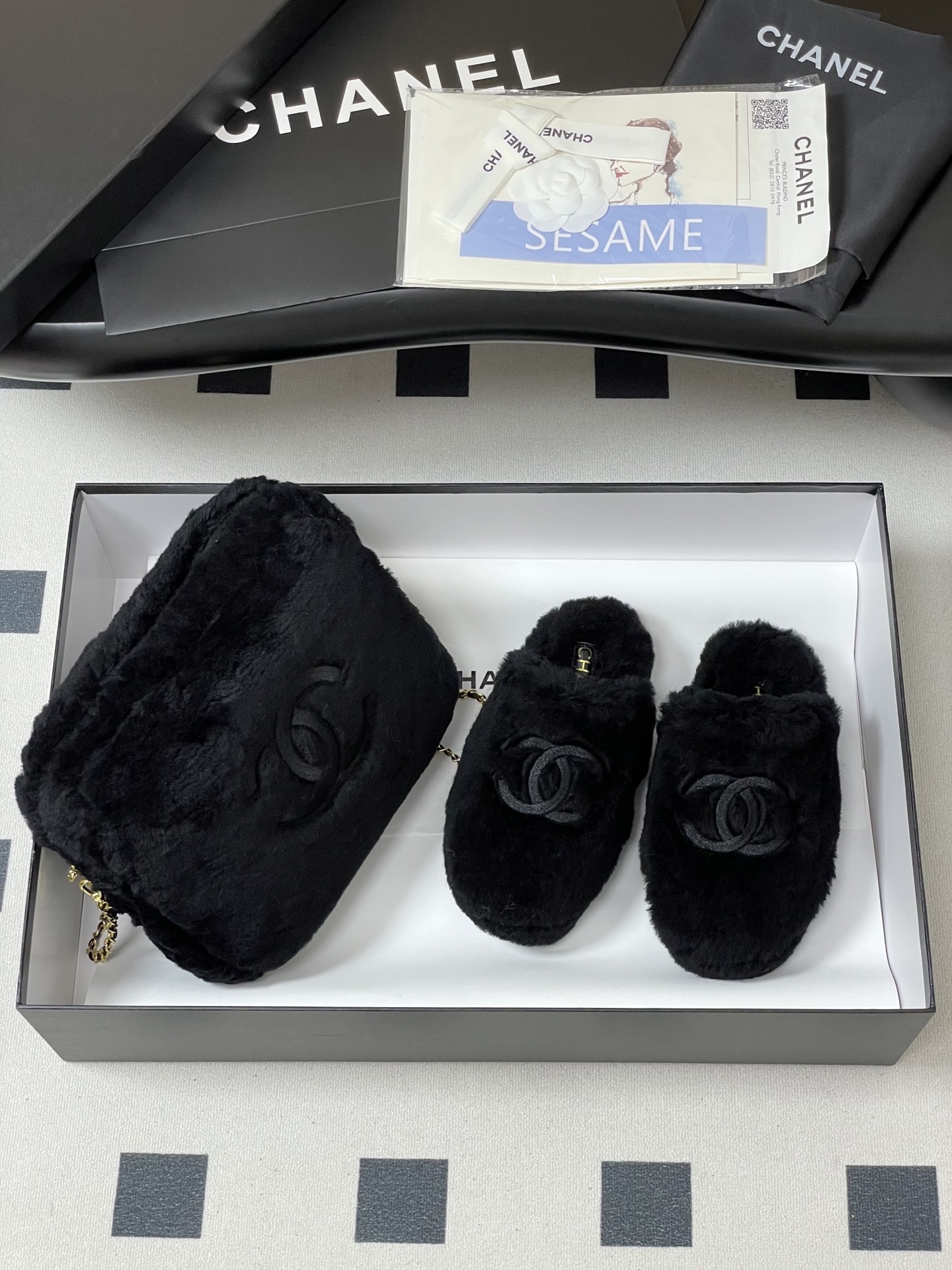 Pair of black plush fuzzy slippers with a grey interlocking CC logo on a black surface - Hình 4