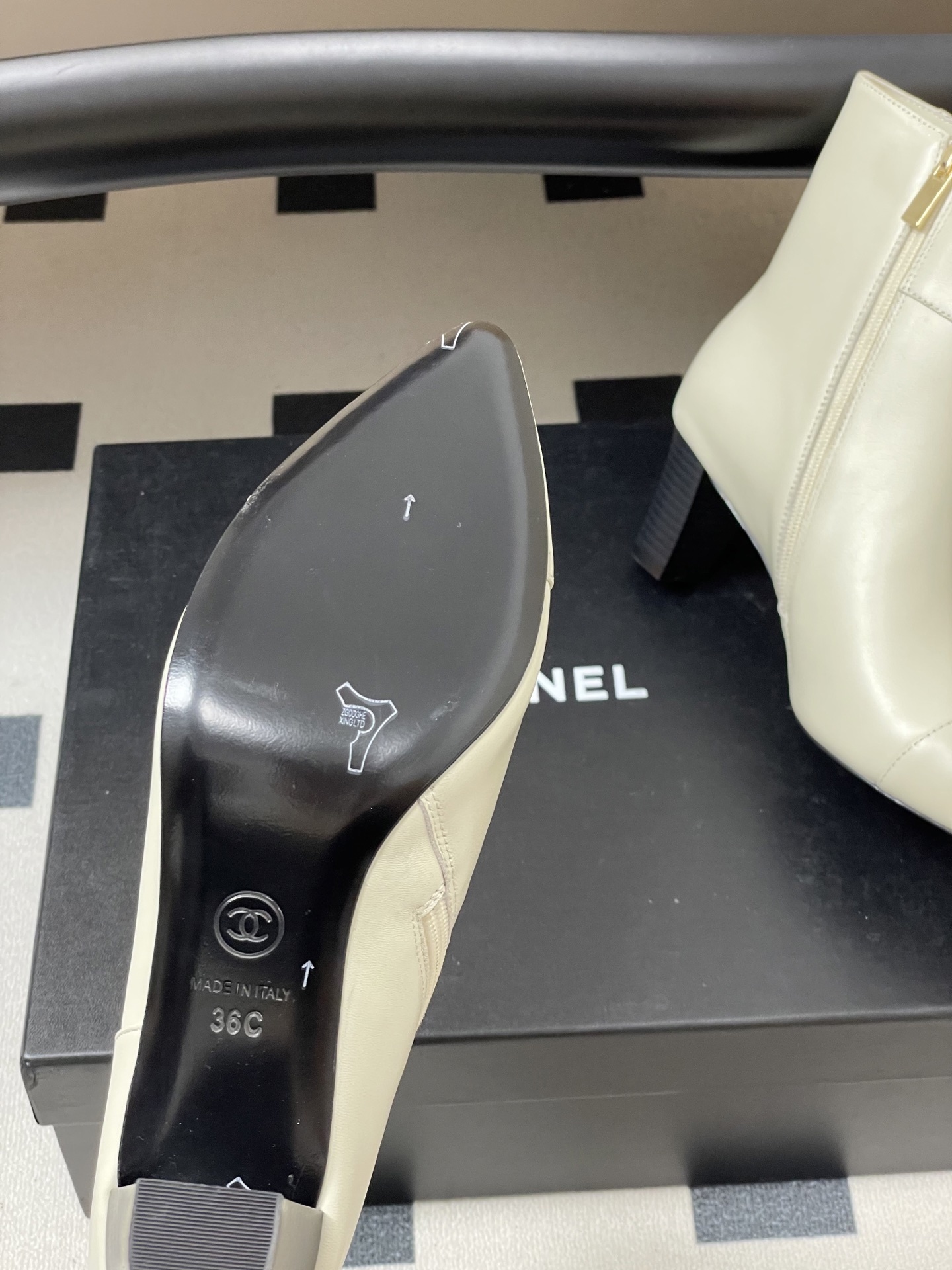 Pair of creamy white leather ankle boots with gold lion head hardware and pointed toe on a black surface - Hình 7