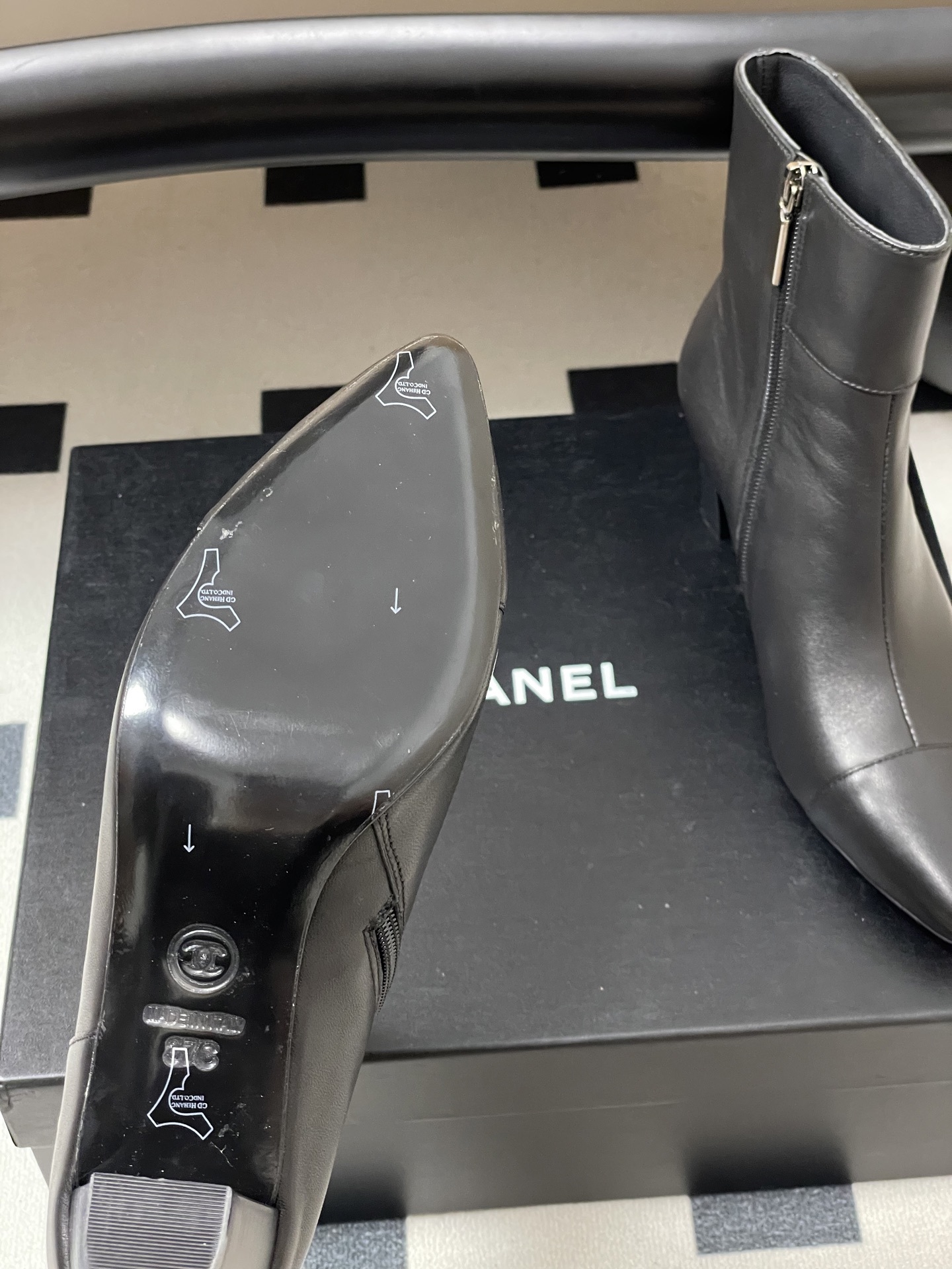 Pair of premium black leather ankle boots with pointed toes and gold lion head decorations on a black surface. - Hình 8