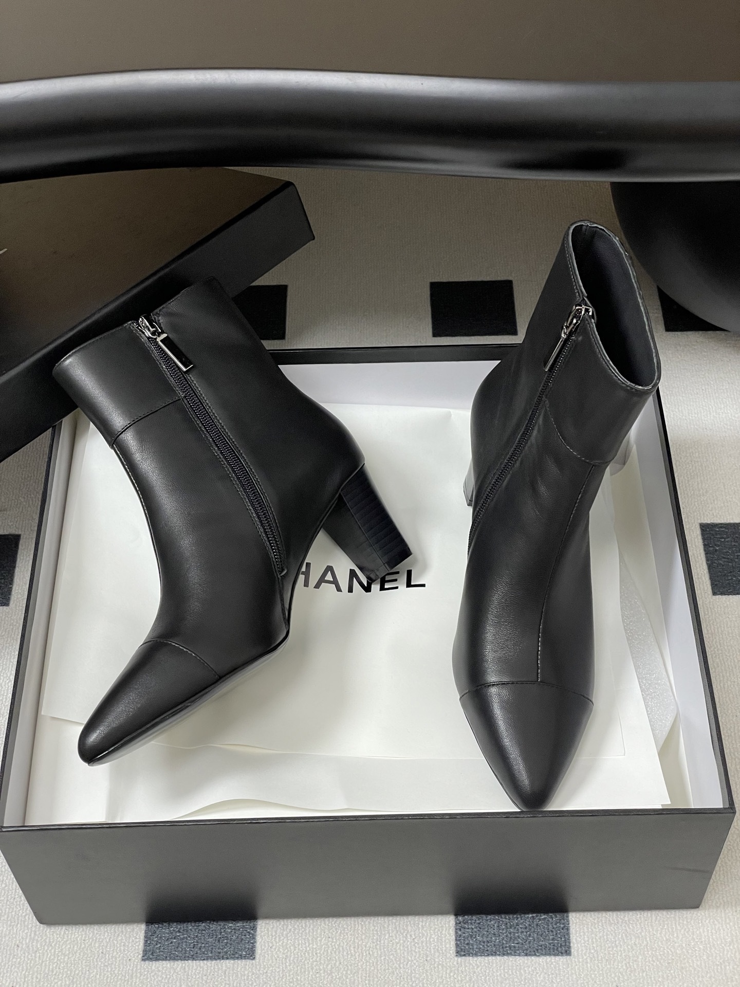 Pair of premium black leather ankle boots with pointed toes and gold lion head decorations on a black surface. - Hình 6