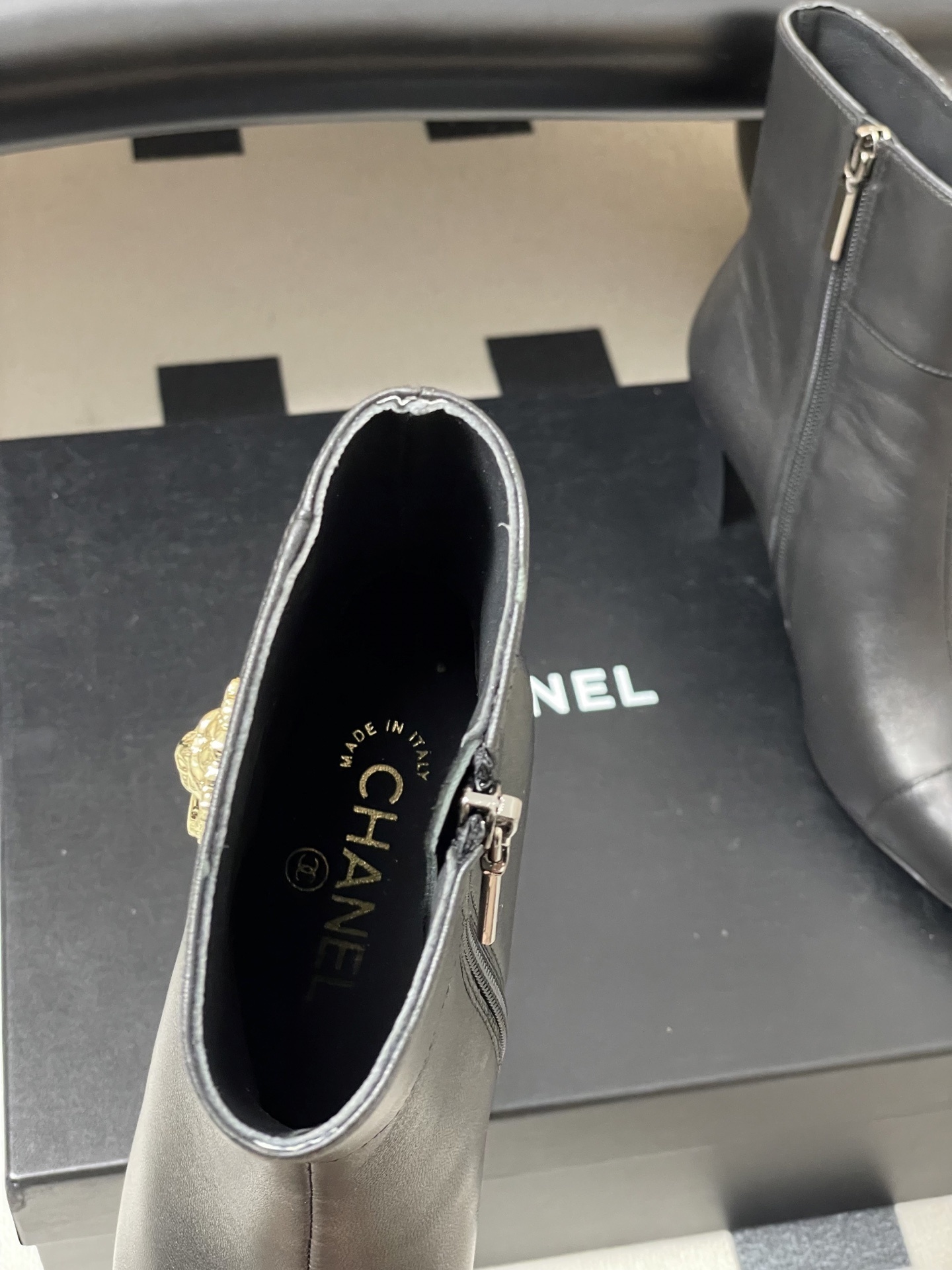 Pair of premium black leather ankle boots with pointed toes and gold lion head decorations on a black surface. - Hình 5